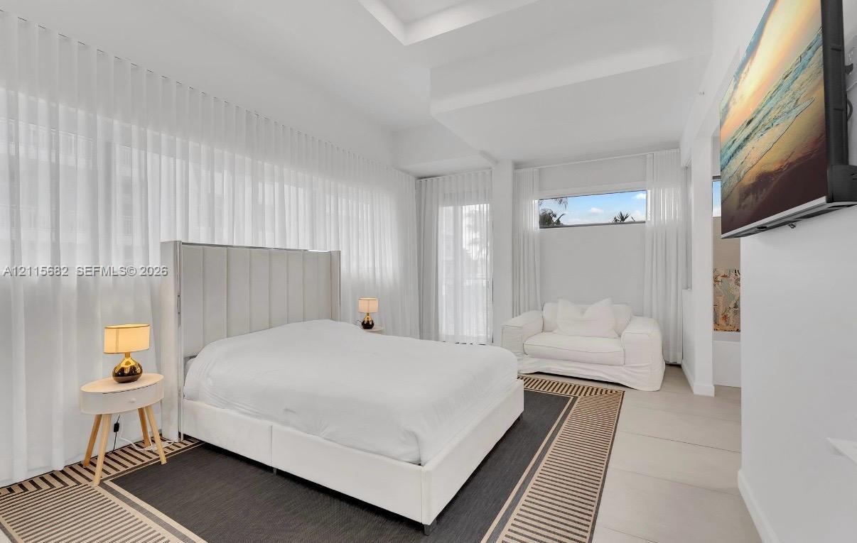 Tray ceiling, floor-to-ceiling sheer window treatments, transom windows, and light-tone tile flooring