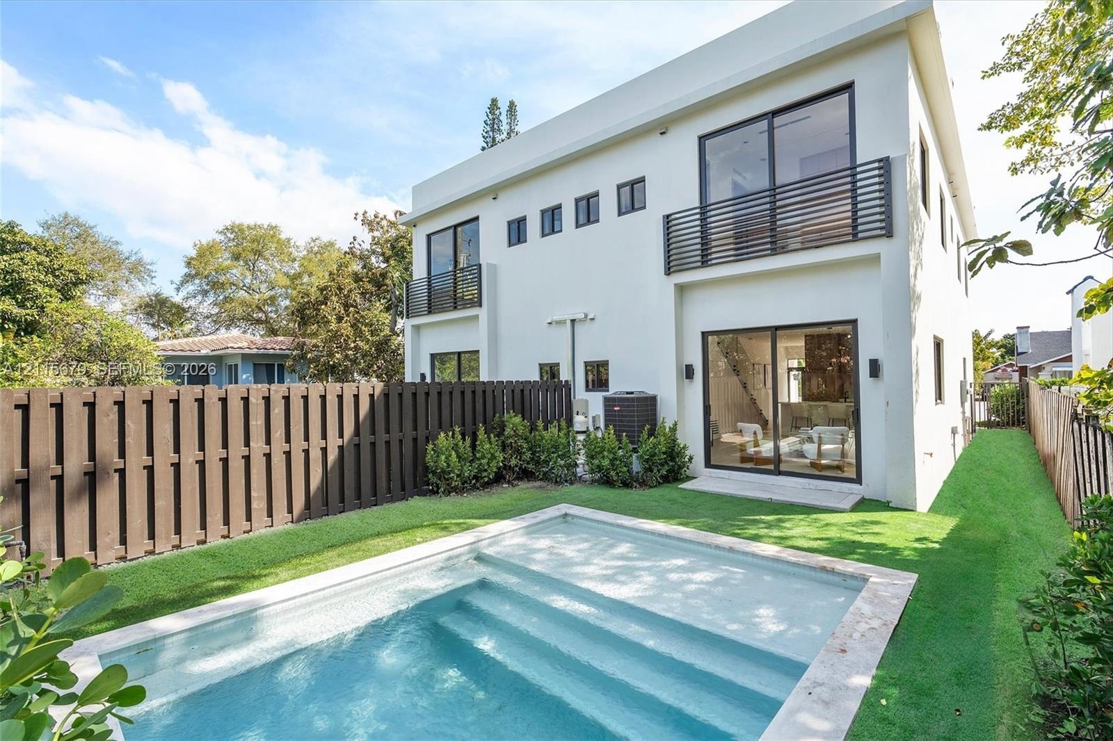 Modern two-story exterior featuring a private swimming pool with built-in steps, second-floor balconies with horizontal railings, sliding glass doors,