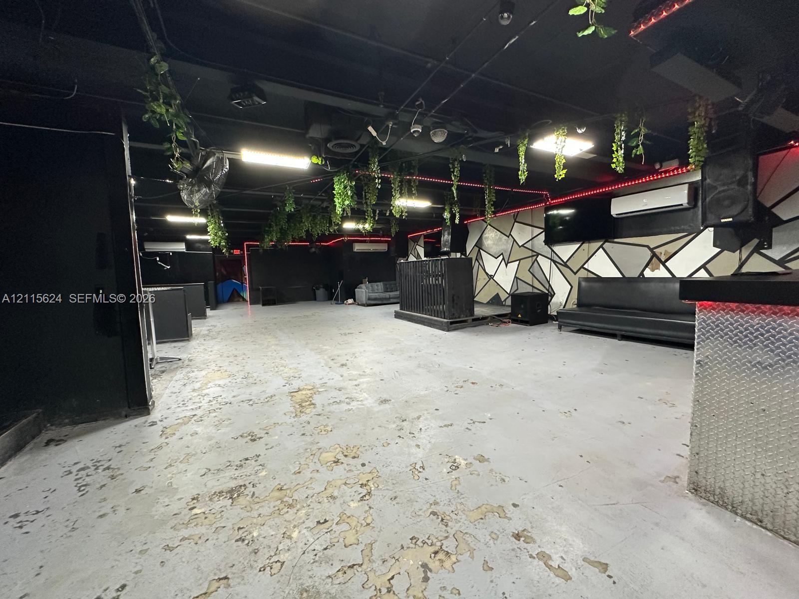 Open-concept interior featuring exposed ceiling rafters, diamond-plate metal bar detailing, and geometric wall paneling