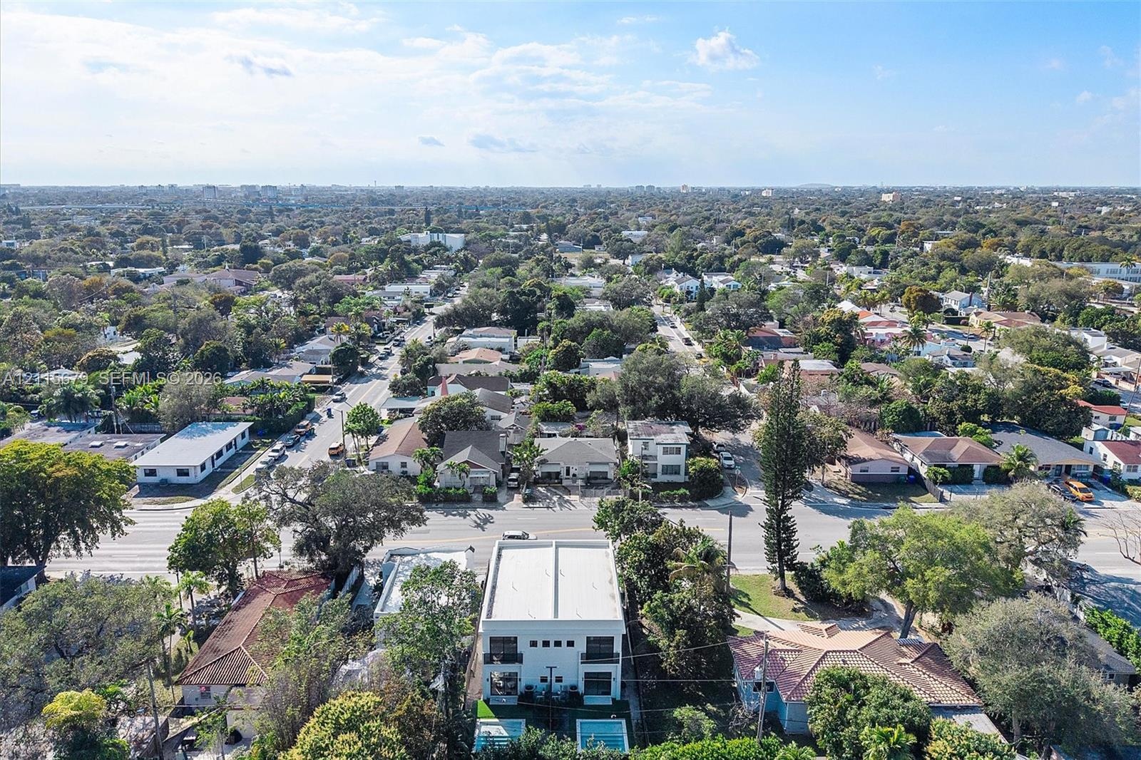 Aerial perspective of a multi-story residence featuring a flat roofline, two levels of balcony structures, a ground-level rectangular swimming pool, a