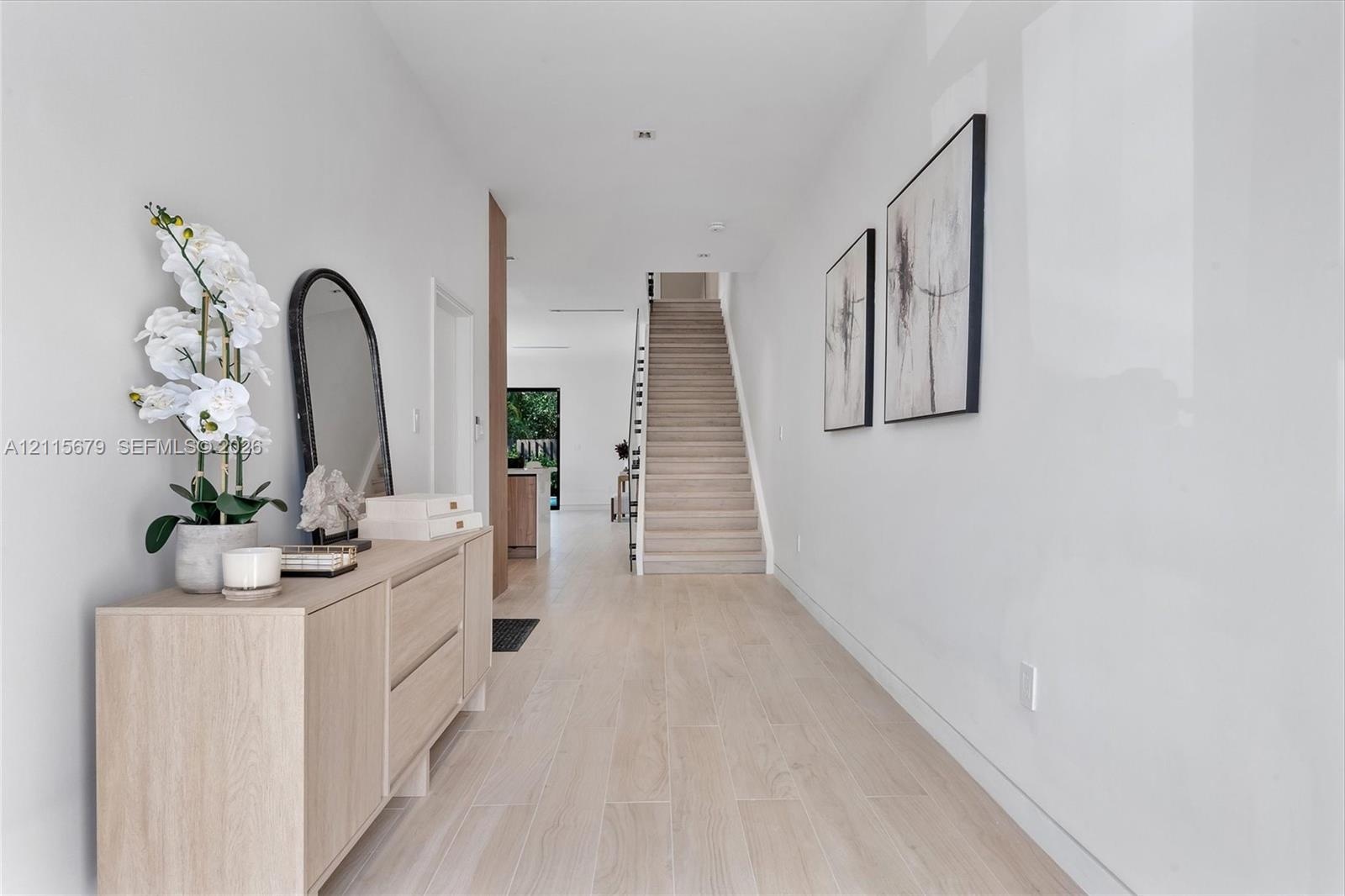 Foyer featuring wood-finish flooring, a neutral color palette, and a staircase with open riser steps