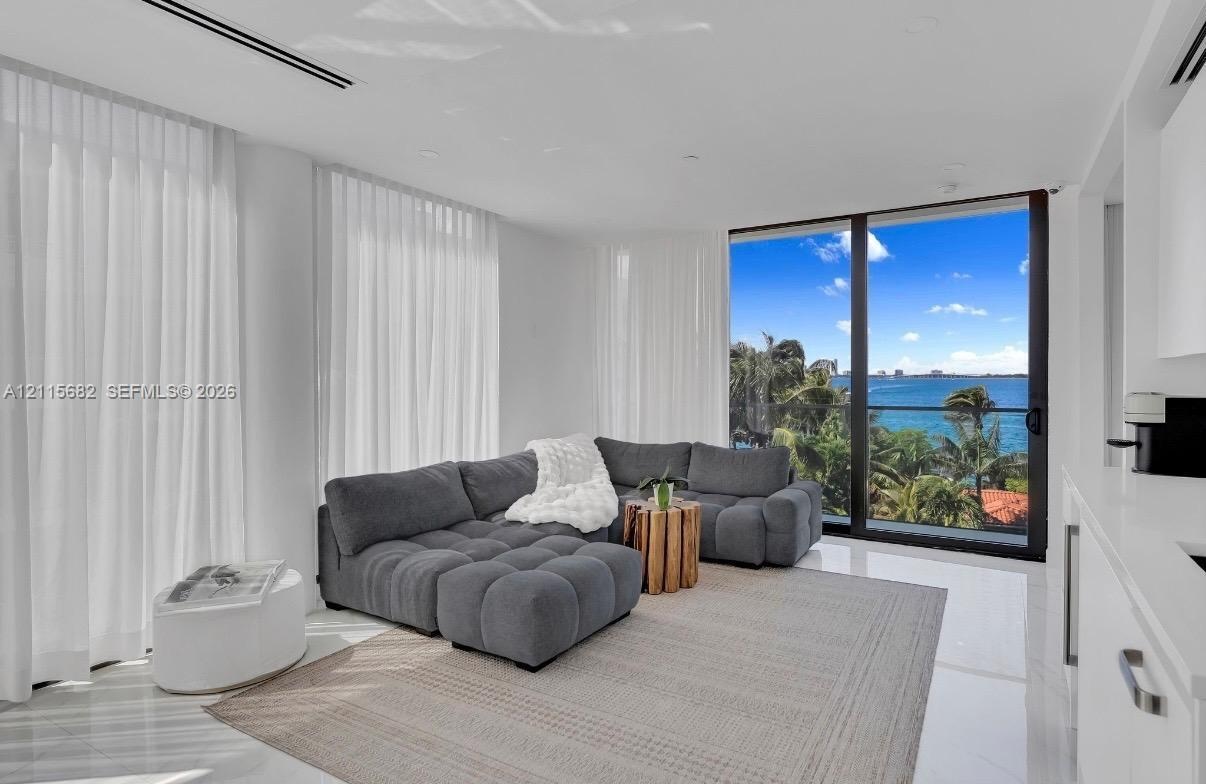 Floor-to-ceiling glass sliding doors, polished stone flooring, recessed ceiling lighting, and expansive water exposure