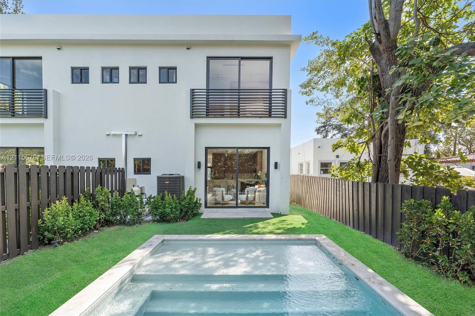 Contemporary two-story exterior featuring smooth stucco finish, black horizontal balcony railings, sliding glass doors, a rectangular swimming pool, a