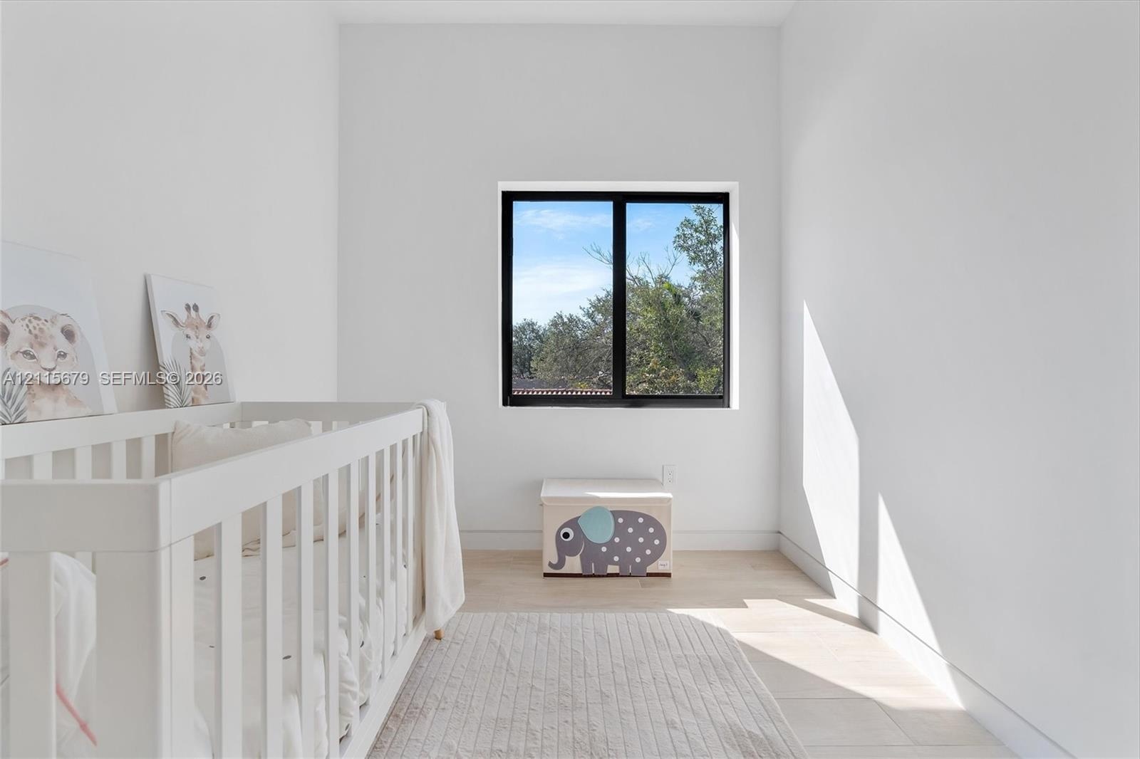 High-ceilinged room featuring wood-finish flooring and a black-framed window