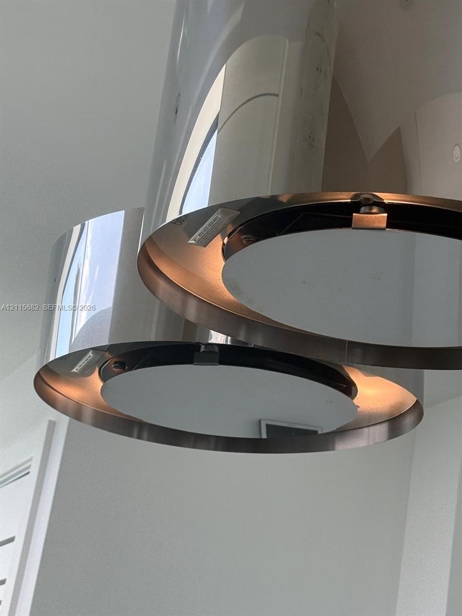 Polished chrome tiered pendant lighting fixture featuring circular metallic bands and integrated illumination
