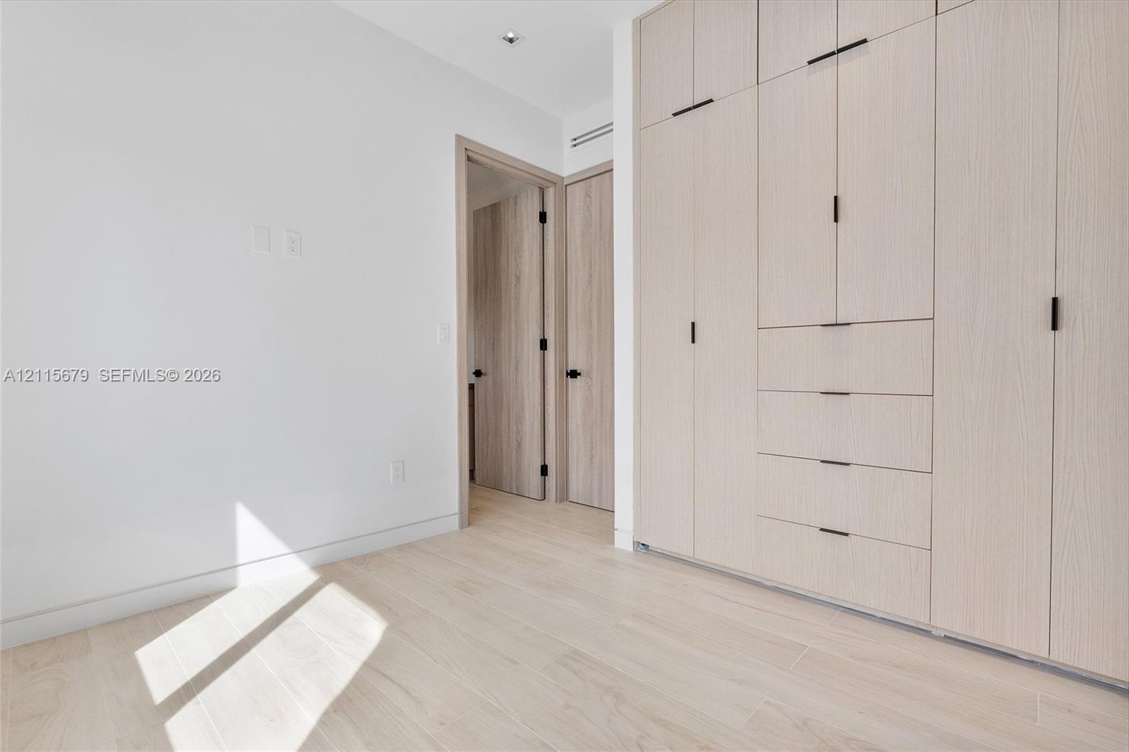 Floor-to-ceiling custom cabinetry with integrated storage, light wood-finish flooring, and recessed ceiling lighting