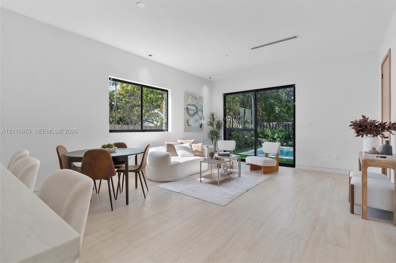 Living area featuring light-toned wood-finish flooring, sliding glass doors, recessed lighting, and a square window