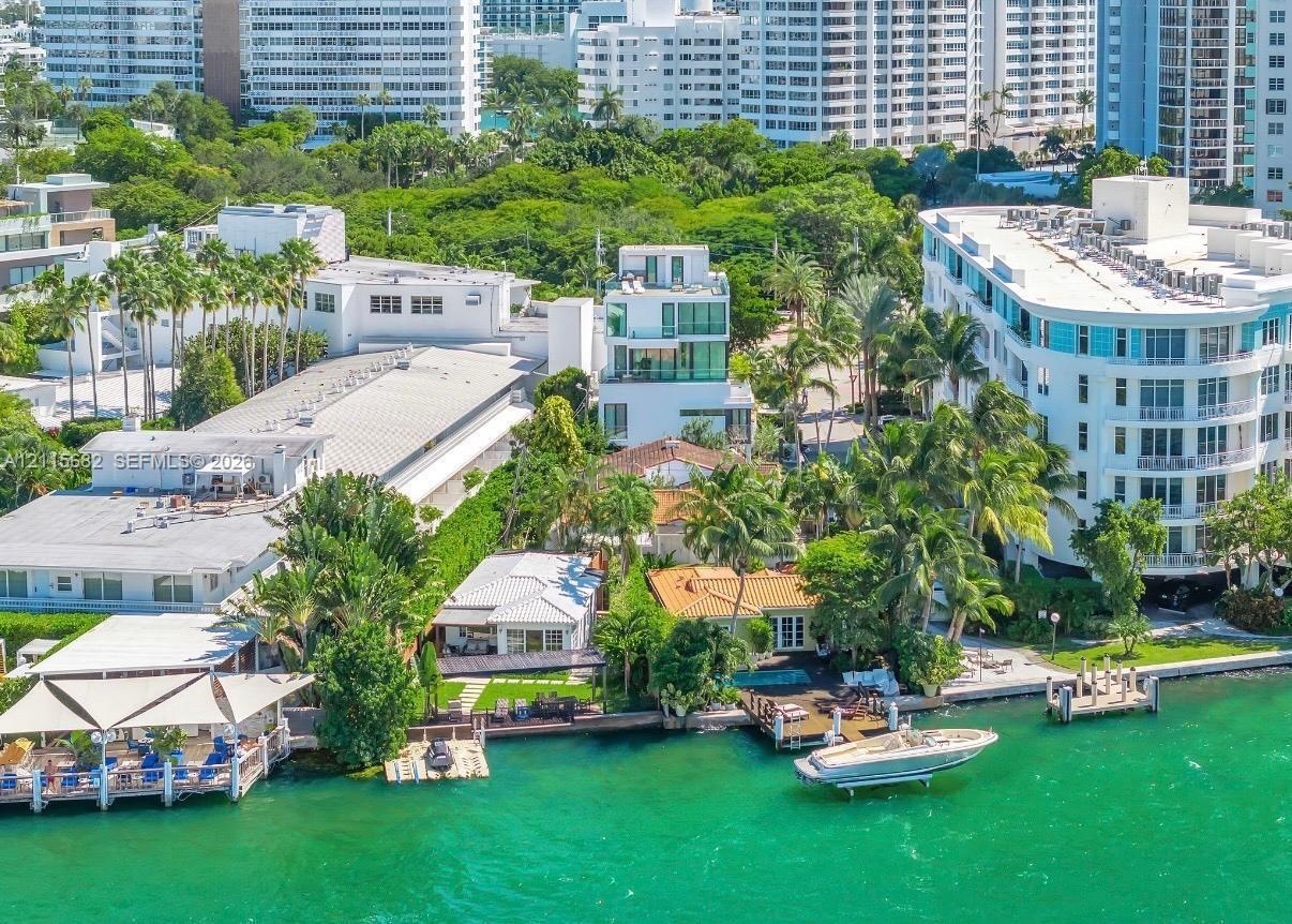 Waterfront estate featuring private boat docks, paved exterior decking, mature landscaping, and multi-level structural design