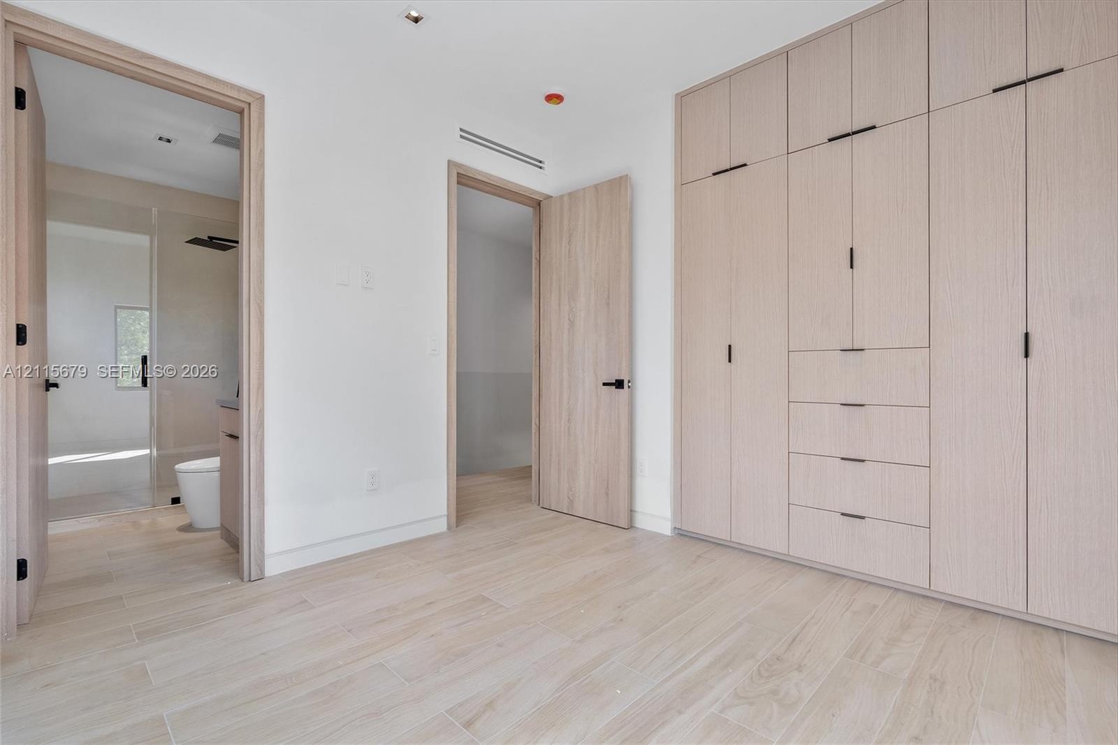 Floor-to-ceiling built-in cabinetry featuring integrated drawers and matte black hardware, wood-finish flooring, and recessed ceiling lighting