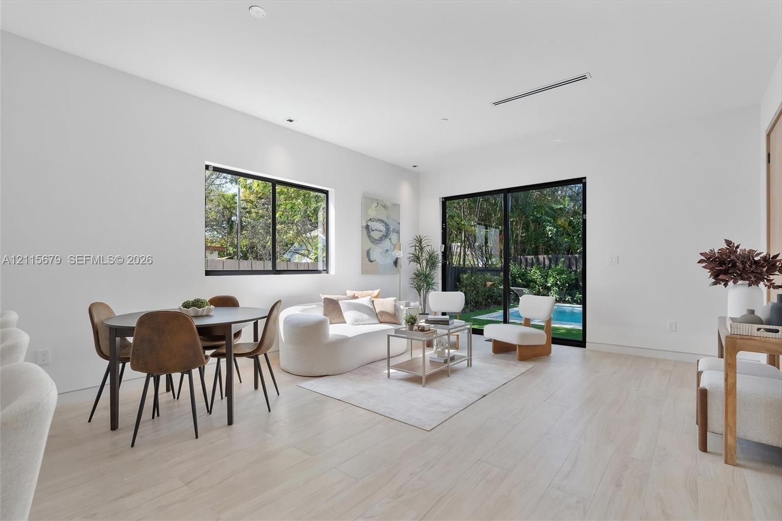 Light-filled living area featuring wood-finish flooring, recessed lighting, and expansive glass sliding doors