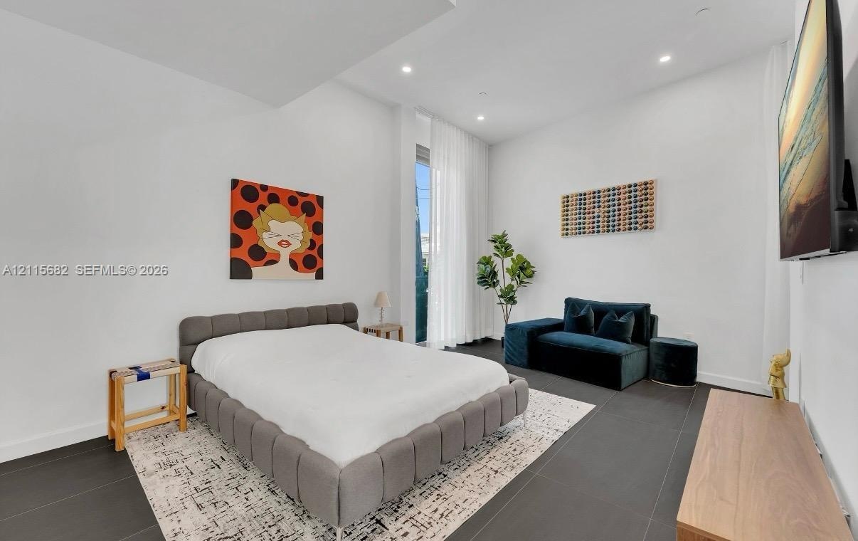 High-ceilinged room featuring large-format dark tile flooring, recessed lighting, and floor-to-ceiling sheer window treatments
