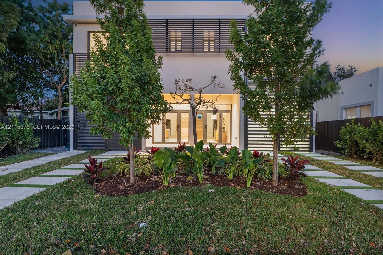 Contemporary exterior featuring clean-lined facade architecture, horizontal slat detailing, dual glass-paneled entry doors, and concrete paver pathway