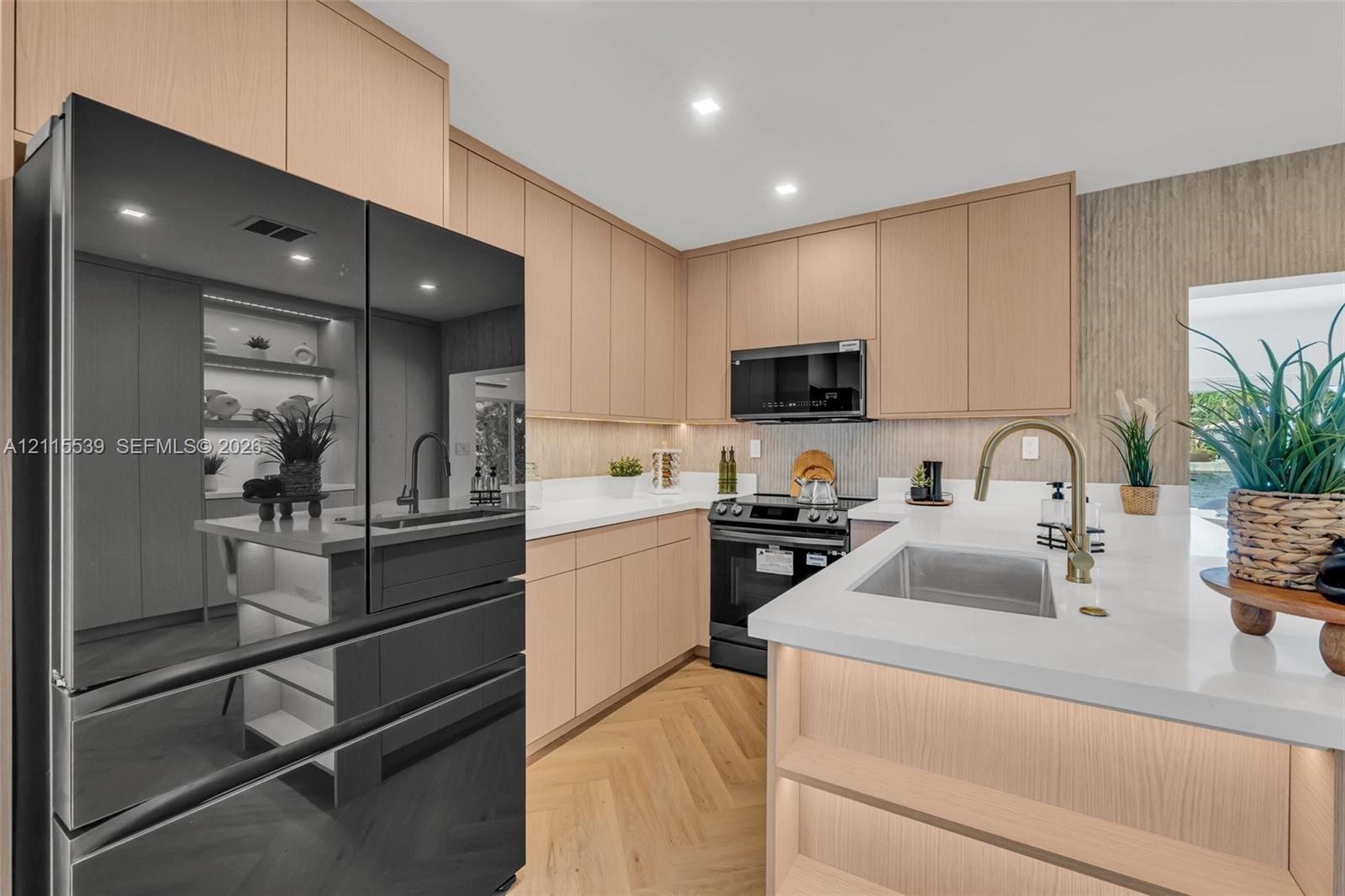 Kitchen featuring flat-panel wood cabinetry, light-toned stone countertops, herringbone-patterned wood flooring, integrated under-cabinet lighting, an