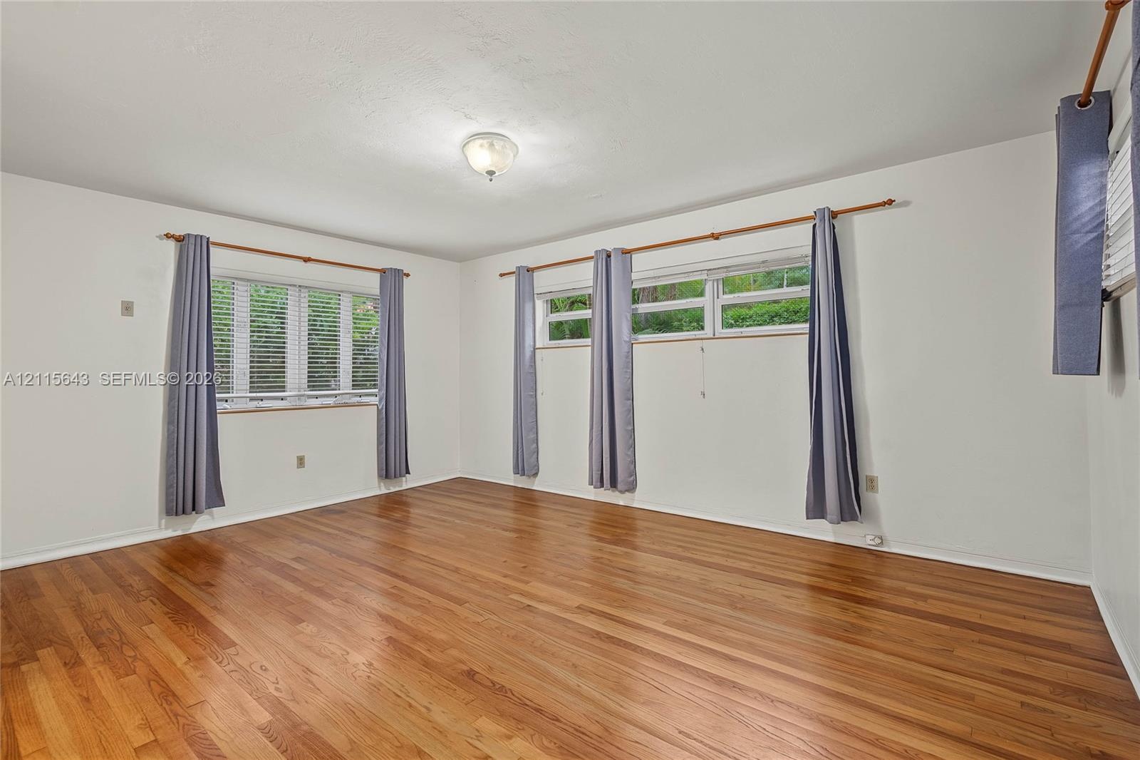 Room featuring wood-finish flooring, multi-pane windows, and a flush-mount ceiling light fixture