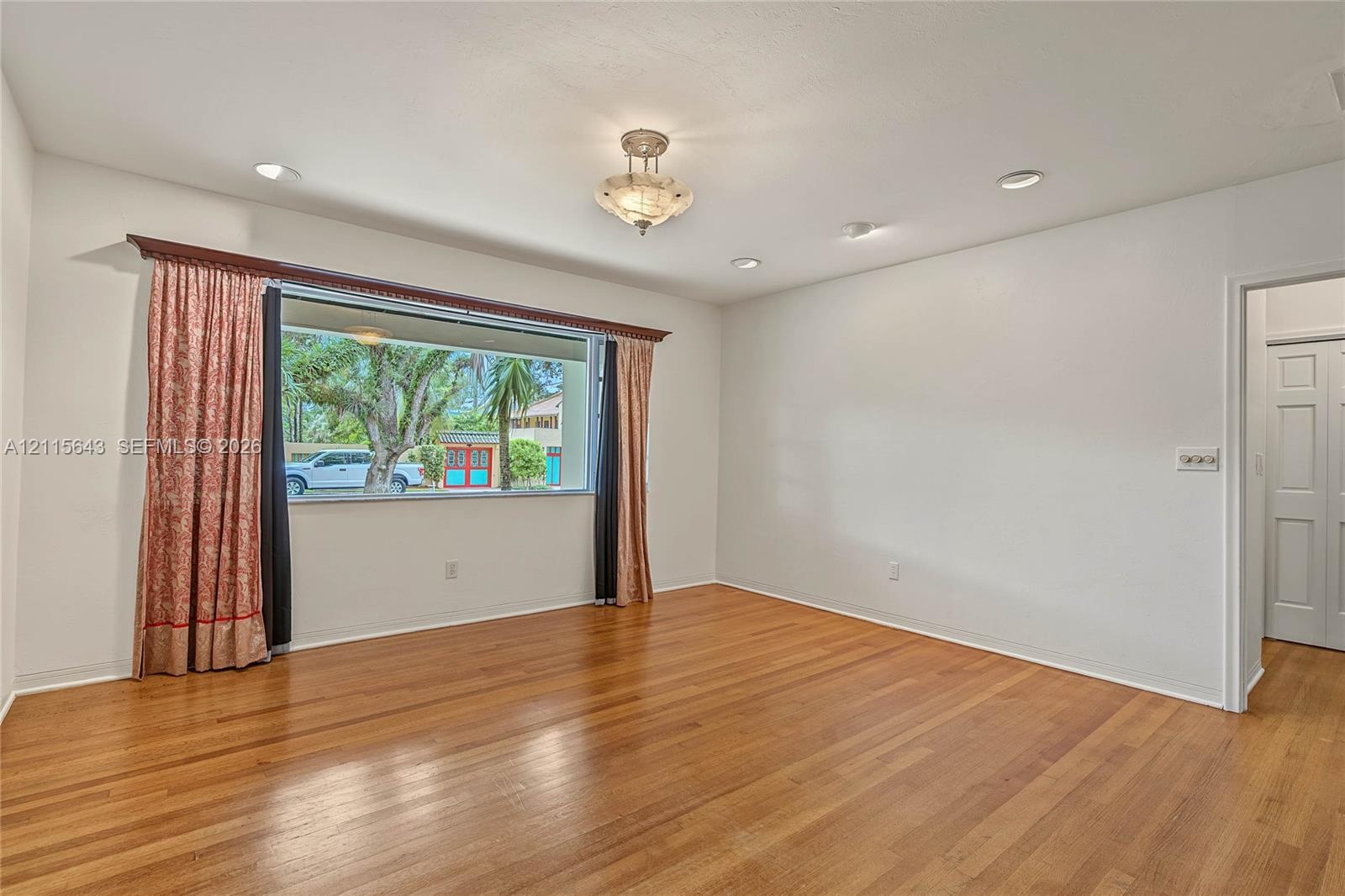 Interior space featuring wood-finish flooring, recessed lighting, a central semi-flush mount light fixture, and a large picture window