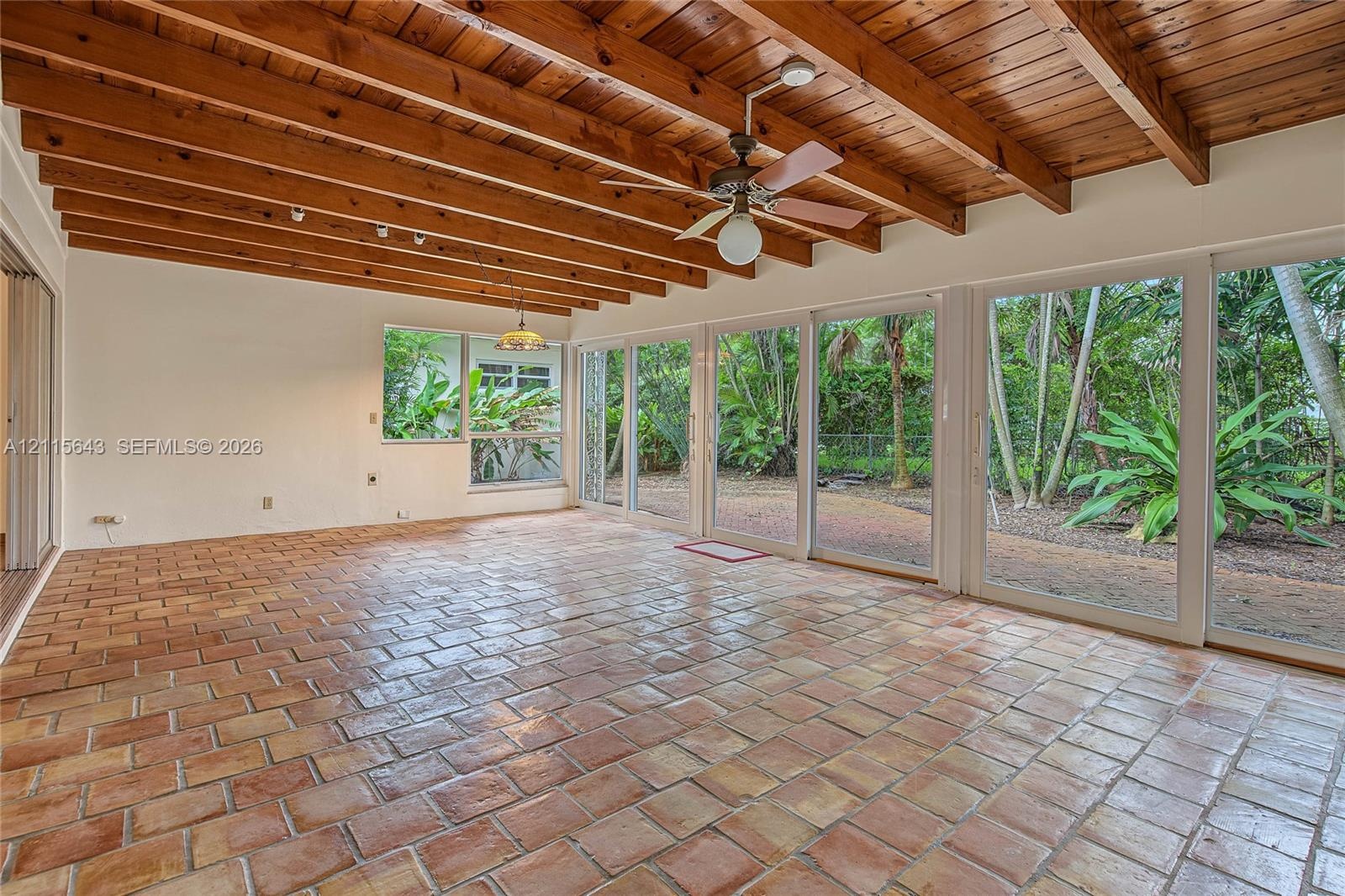 Exposed wood beam ceiling, terracotta tile flooring, and floor-to-ceiling glass sliding doors