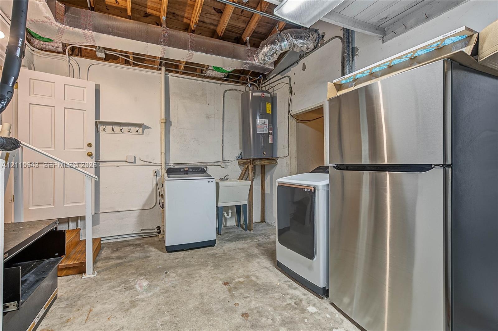 Utility area featuring a top-loading washing machine, electric dryer, stainless steel refrigerator, and integrated utility sink