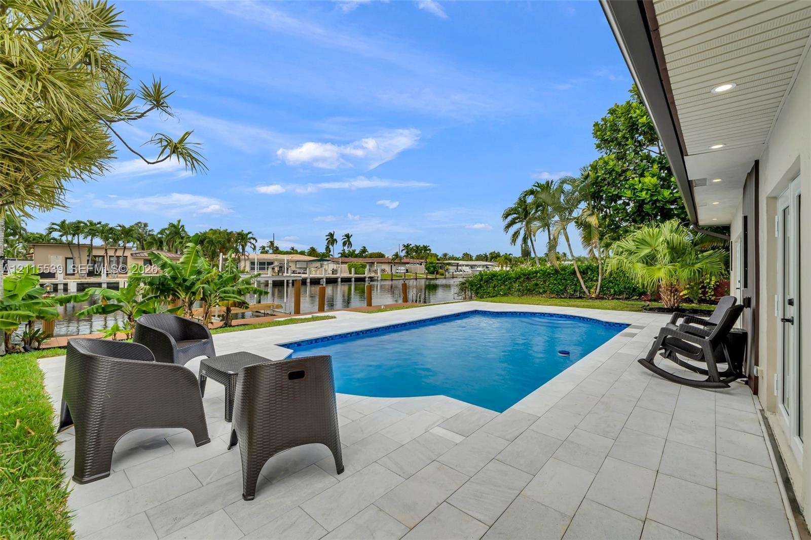 Waterfront swimming pool with a stone paver deck and a recessed soffit featuring integrated lighting