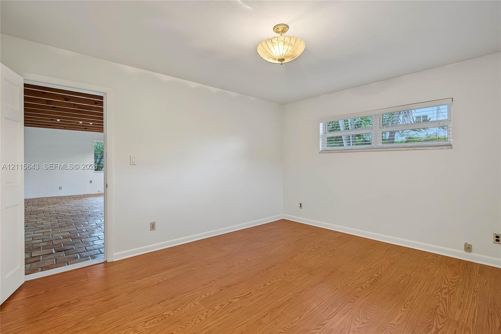 Room featuring wood-finish flooring, a multi-pane horizontal window, and a semi-flush mount light fixture