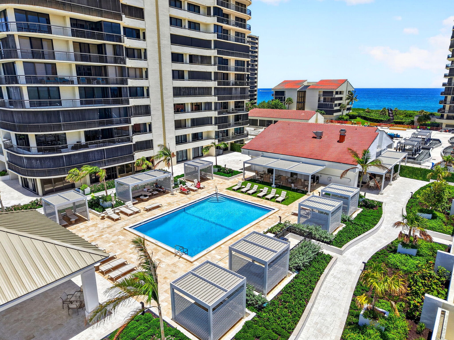 A large covered pavilion on the far left, 1 of 2 swimming pools shown, private cabanas, and The Q Restaurant for residents to enjoy.