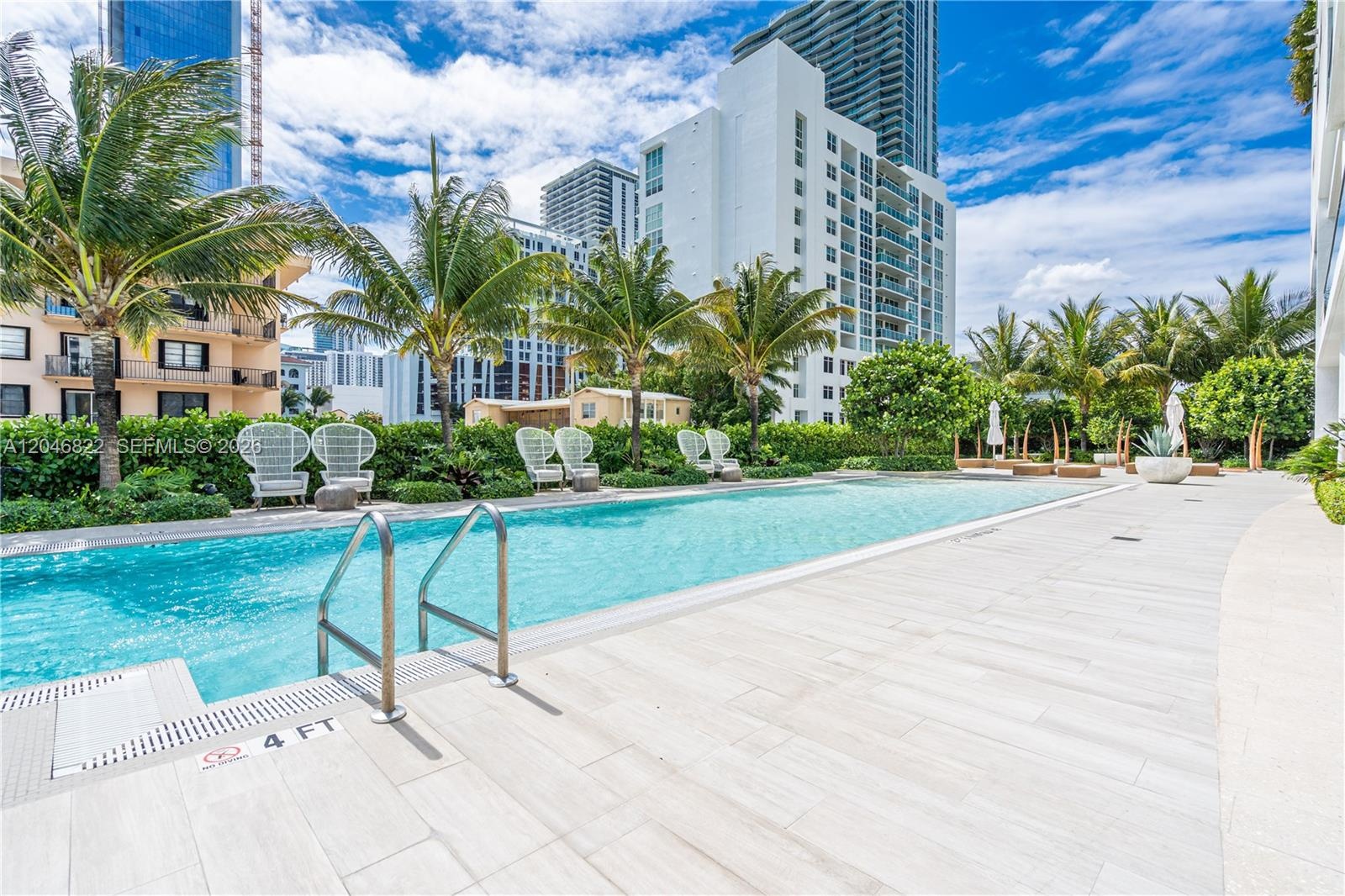 Bayfront lap pool lined with palms and lounge seating