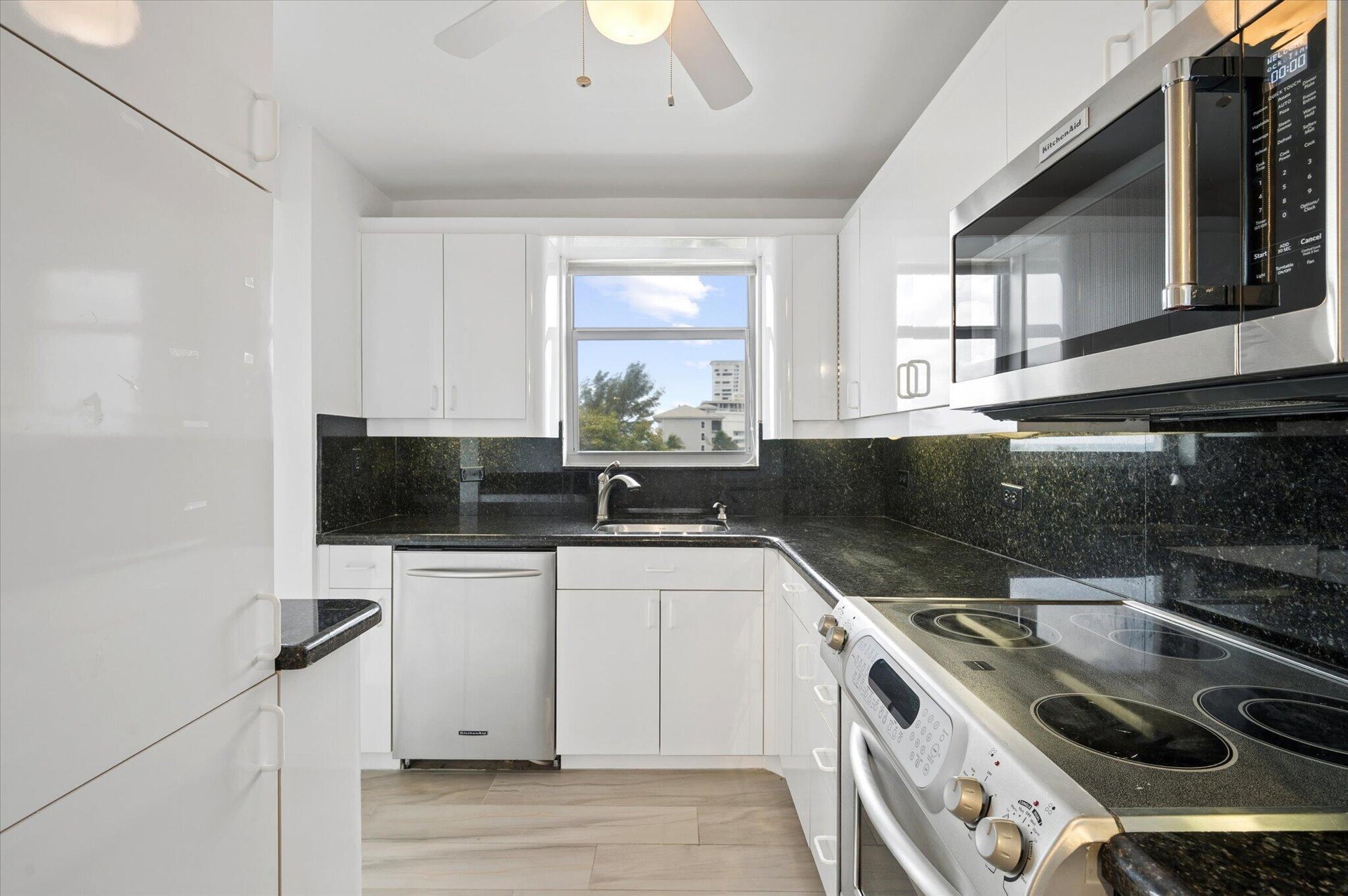 KITCHEN WITH STAINLESS STEEL APPLIANCES AND GRANITE COUNTER TOPS.