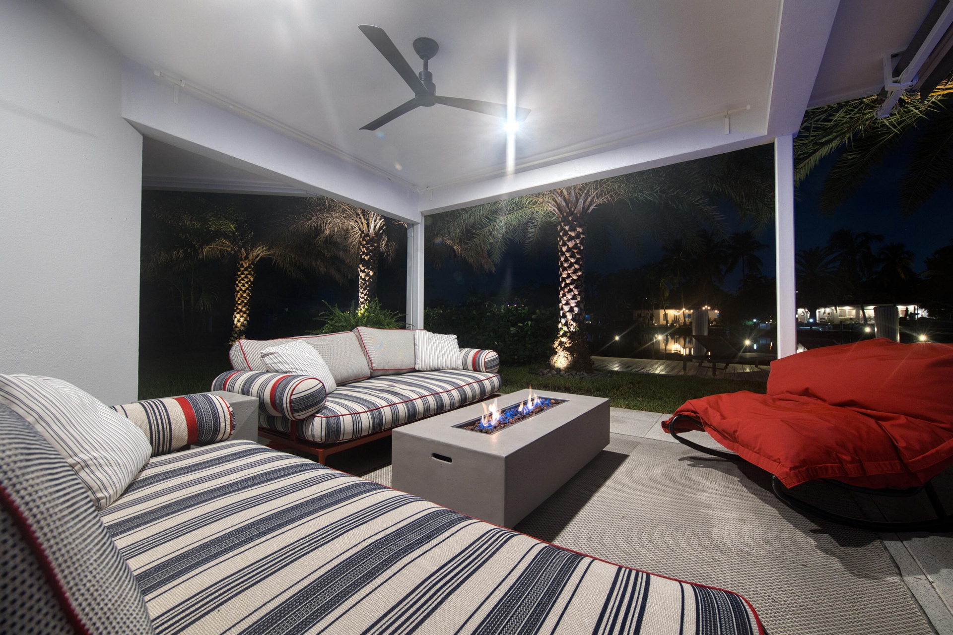 Outdoor kitchen with fire pit at night overlooks waterfront