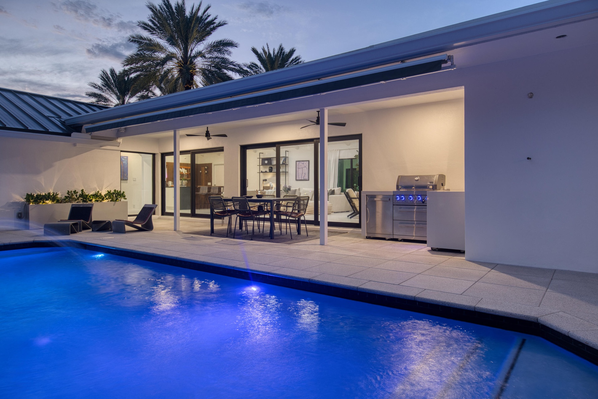 From pool looking at outdoor kitchen, dining and interior of home