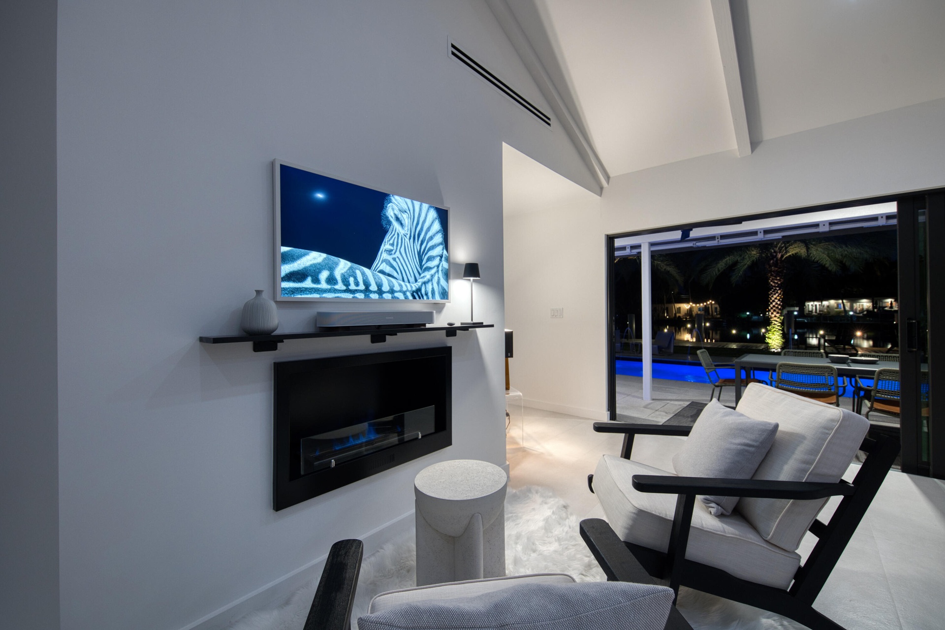 Evening view of additional seating area within the large living room with bio flame fireplace and overlooks the pool