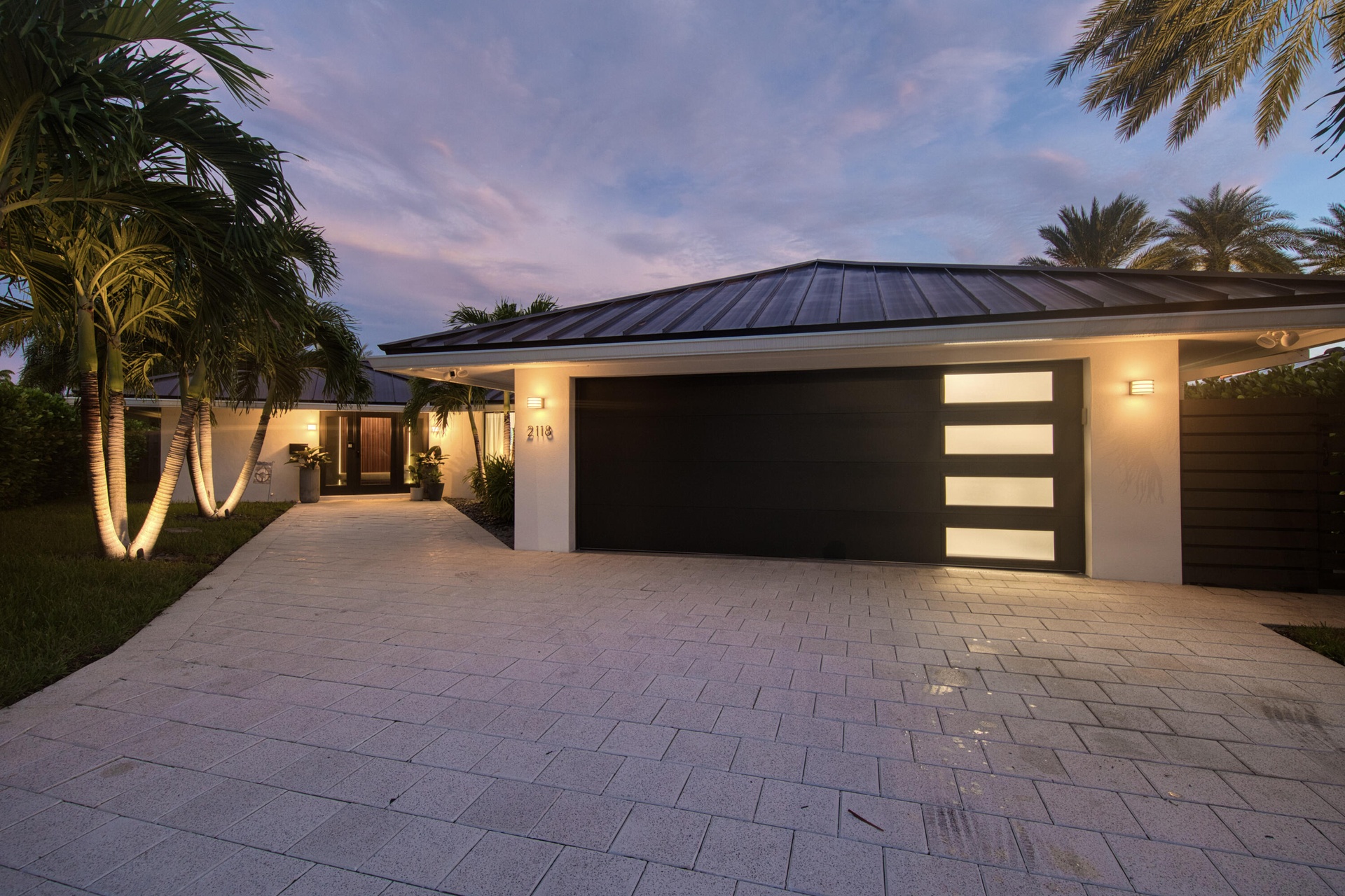 Front wide paver walkway to home, and garage and wide driveway in the evening.