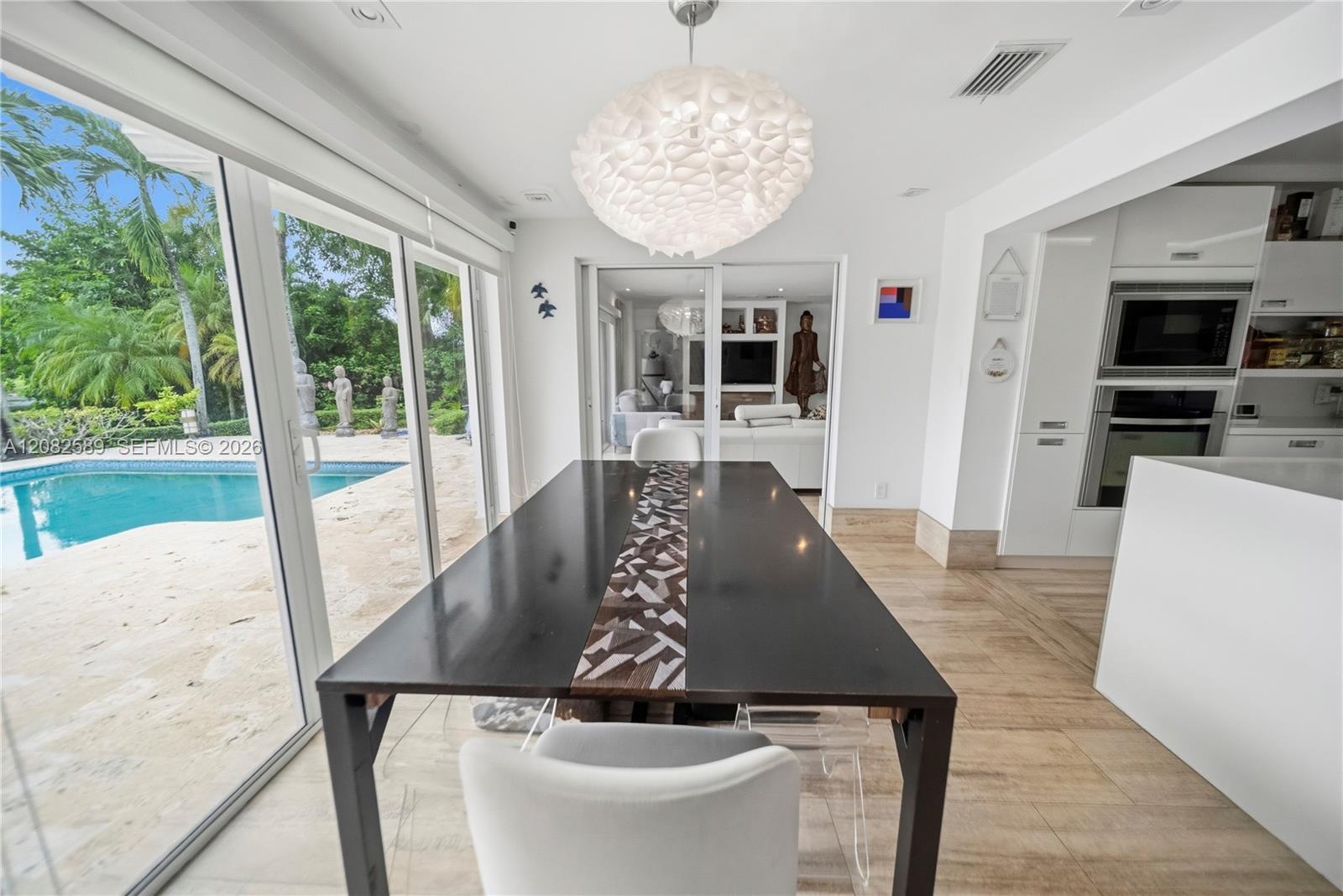 Bright breakfast area with floor-to-ceiling glass doors and beautiful pool views.