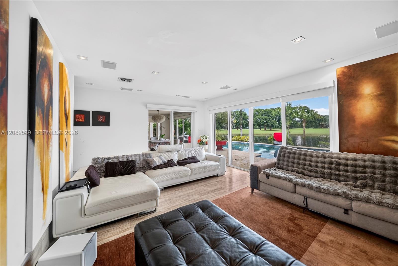 Home theater/media room with expansive glass doors overlooking the pool, lake and golf course, offering flexibility for potential use as a 5th bedroom