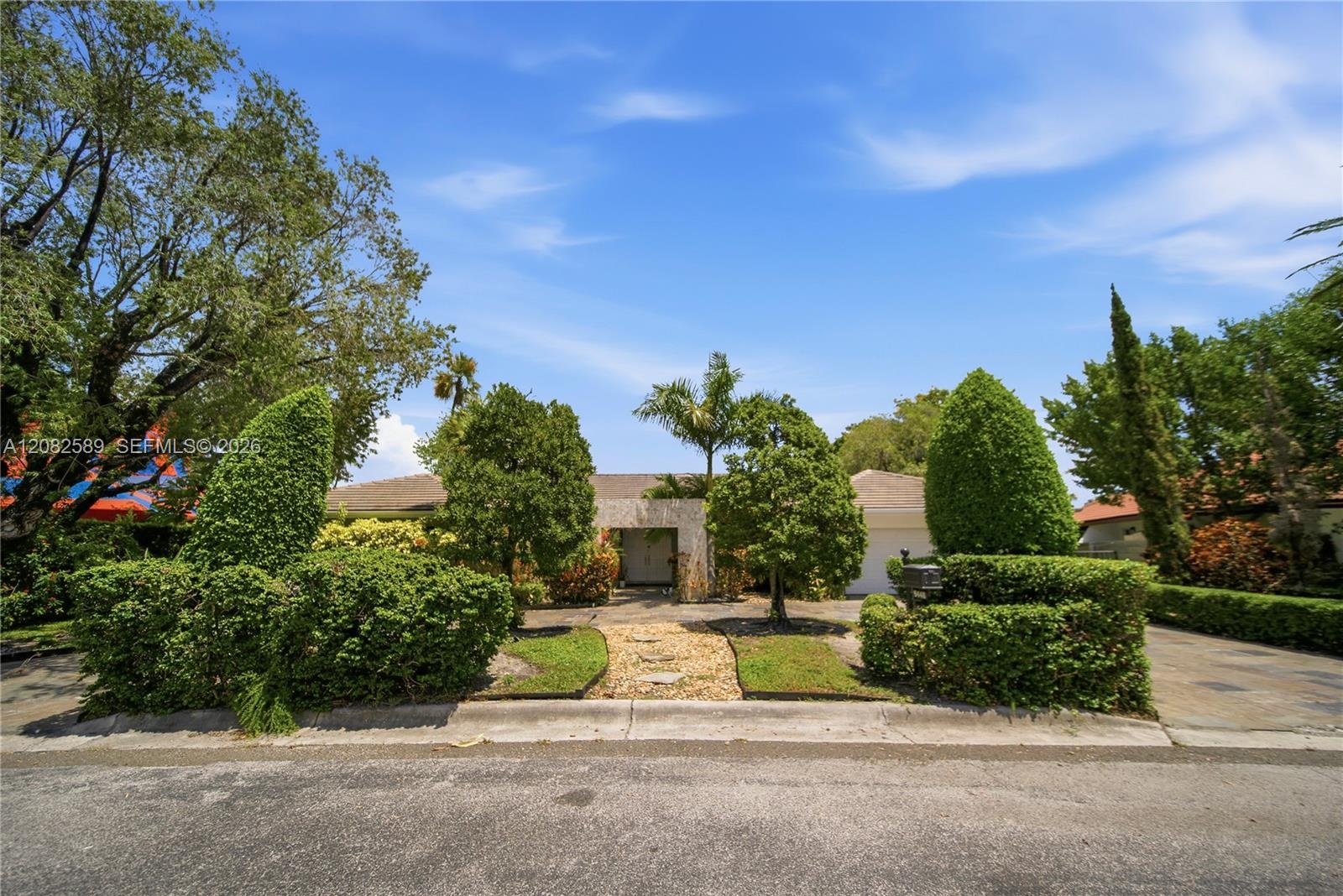 Welcoming front exterior framed by lush, mature landscaping and a private, elegant entrance.