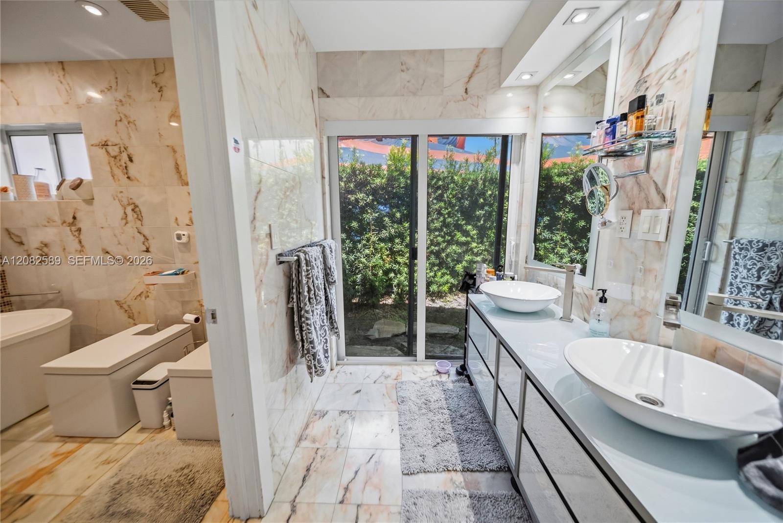 Luxurious primary bathroom featuring dual vessel sinks, marble finishes, and abundant natural light.