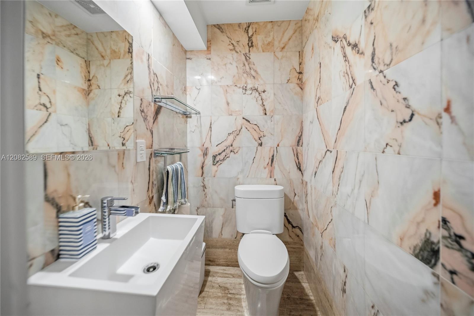 A stylish powder room featuring sleek fixtures and beautiful marble-inspired finishes.