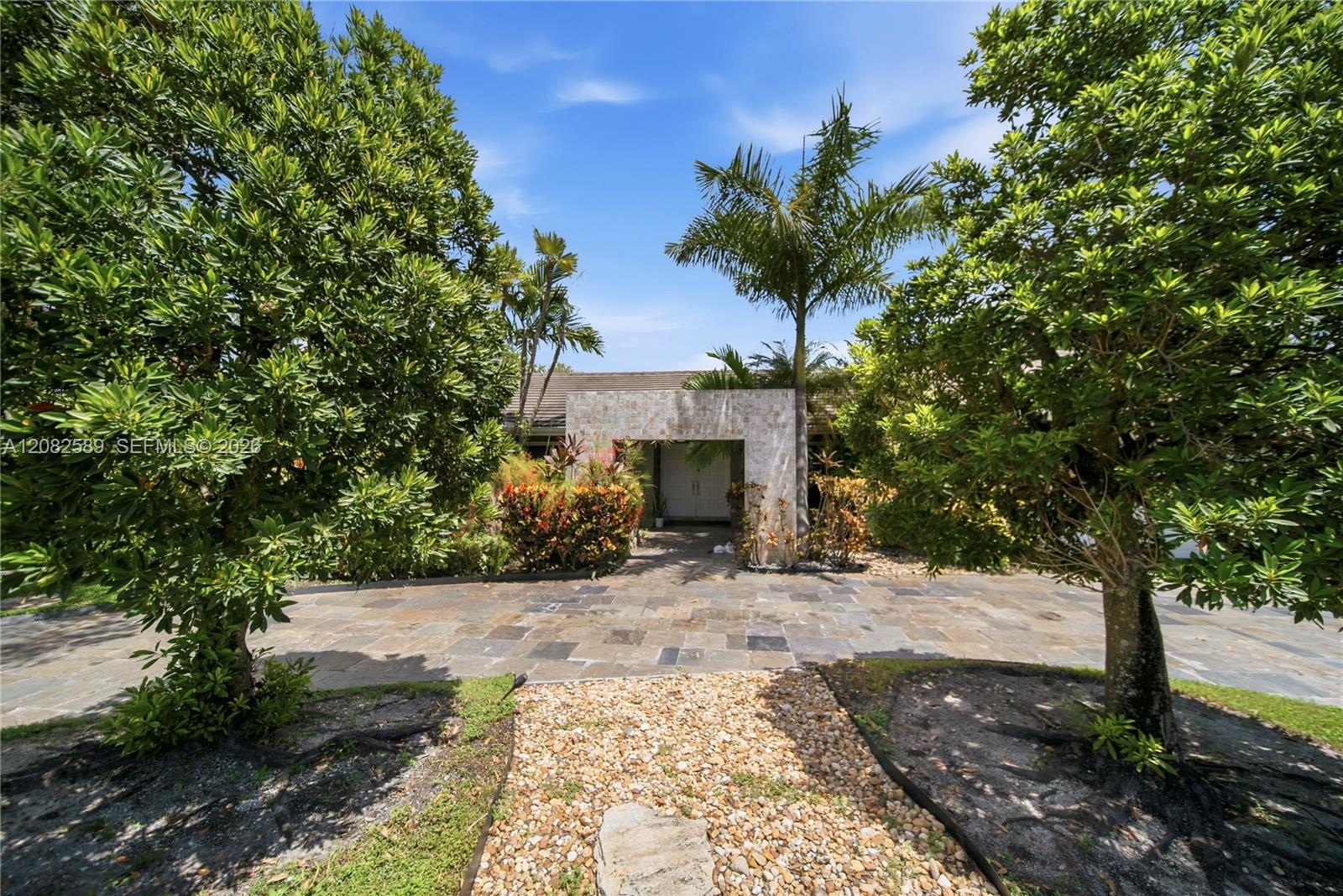 Beautifully landscaped front approach framed by mature tropical greenery, offering a private and inviting entrance.