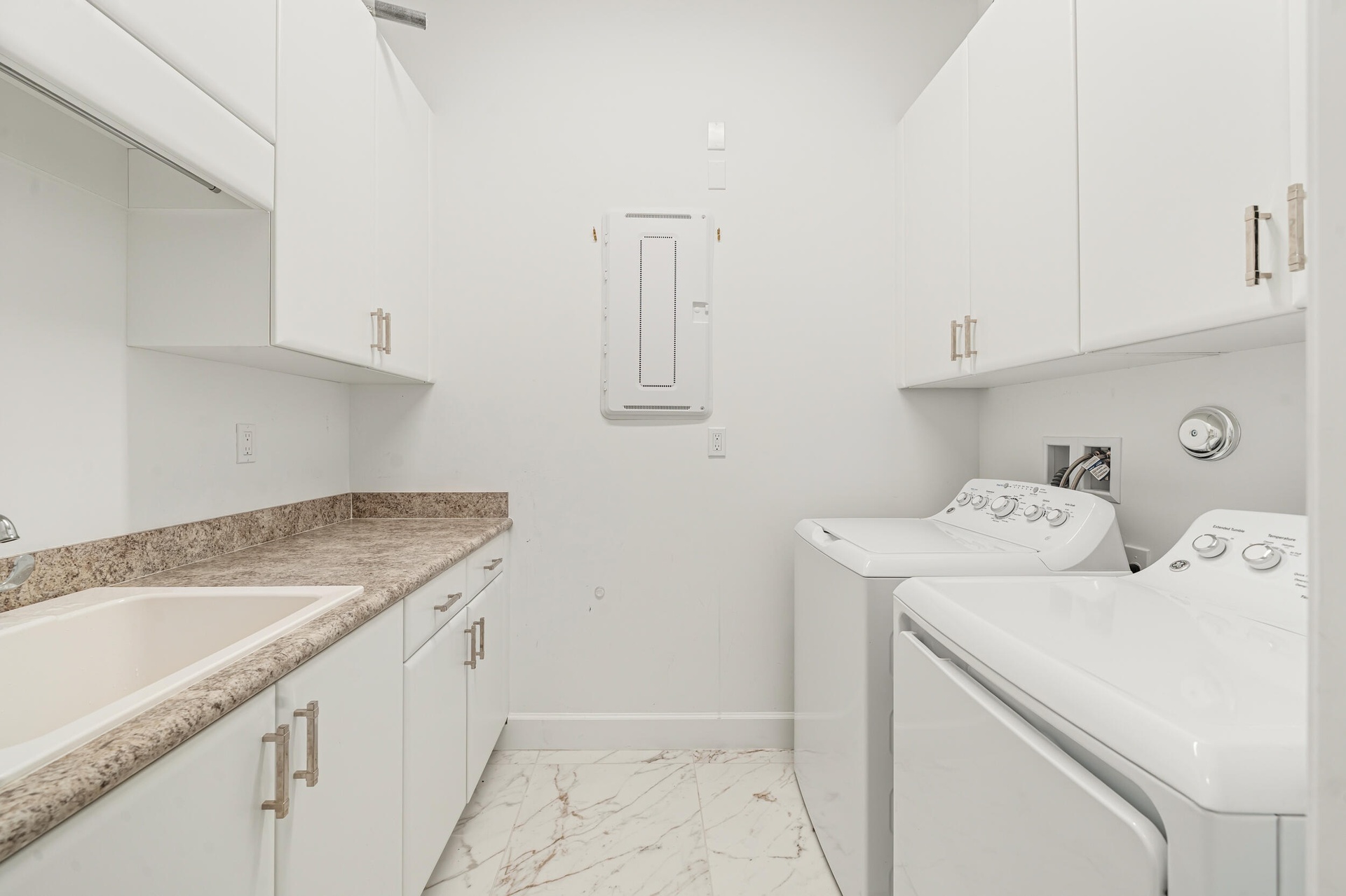 Spacious laundry room with built-in cabinetry and utility sink.