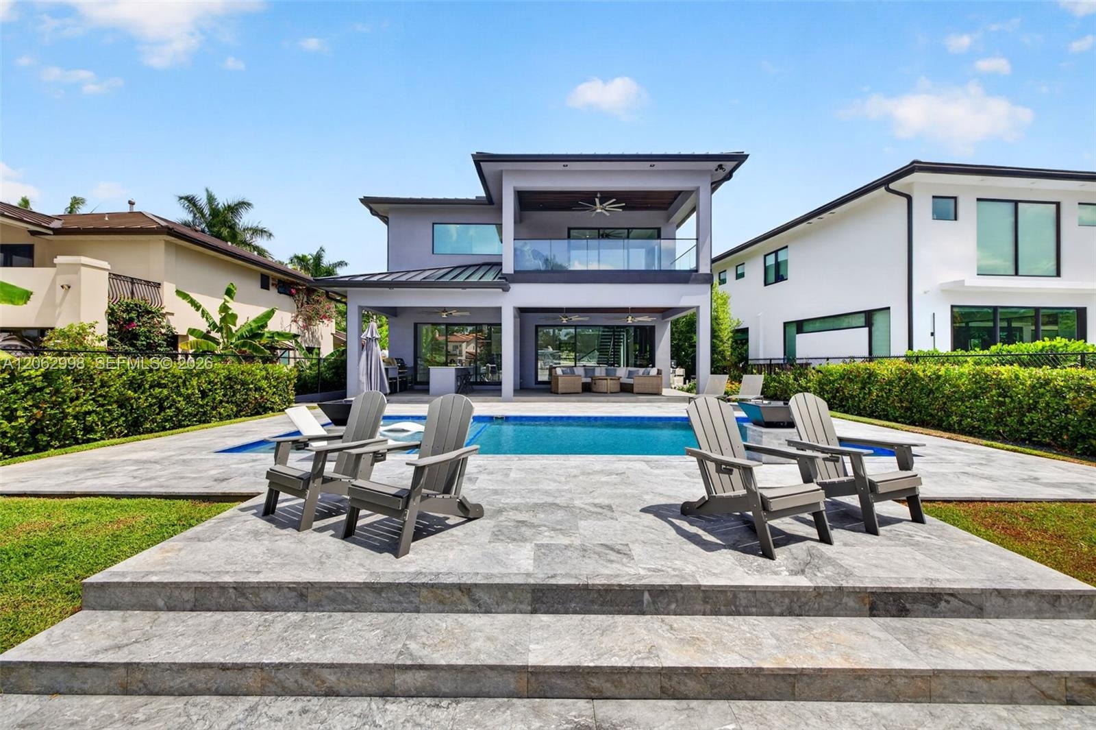 View from the new concrete dock and seawall to the Salt chlorinated pool w/ water features, LED color changing light, sun shelf with umbrella hole and