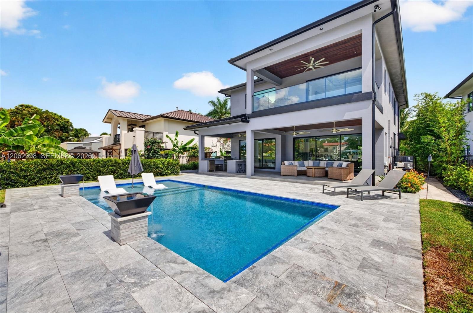 View from the new concrete dock and seawall to the Salt chlorinated pool w/ water features, LED color changing light, sun shelf with umbrella hole and