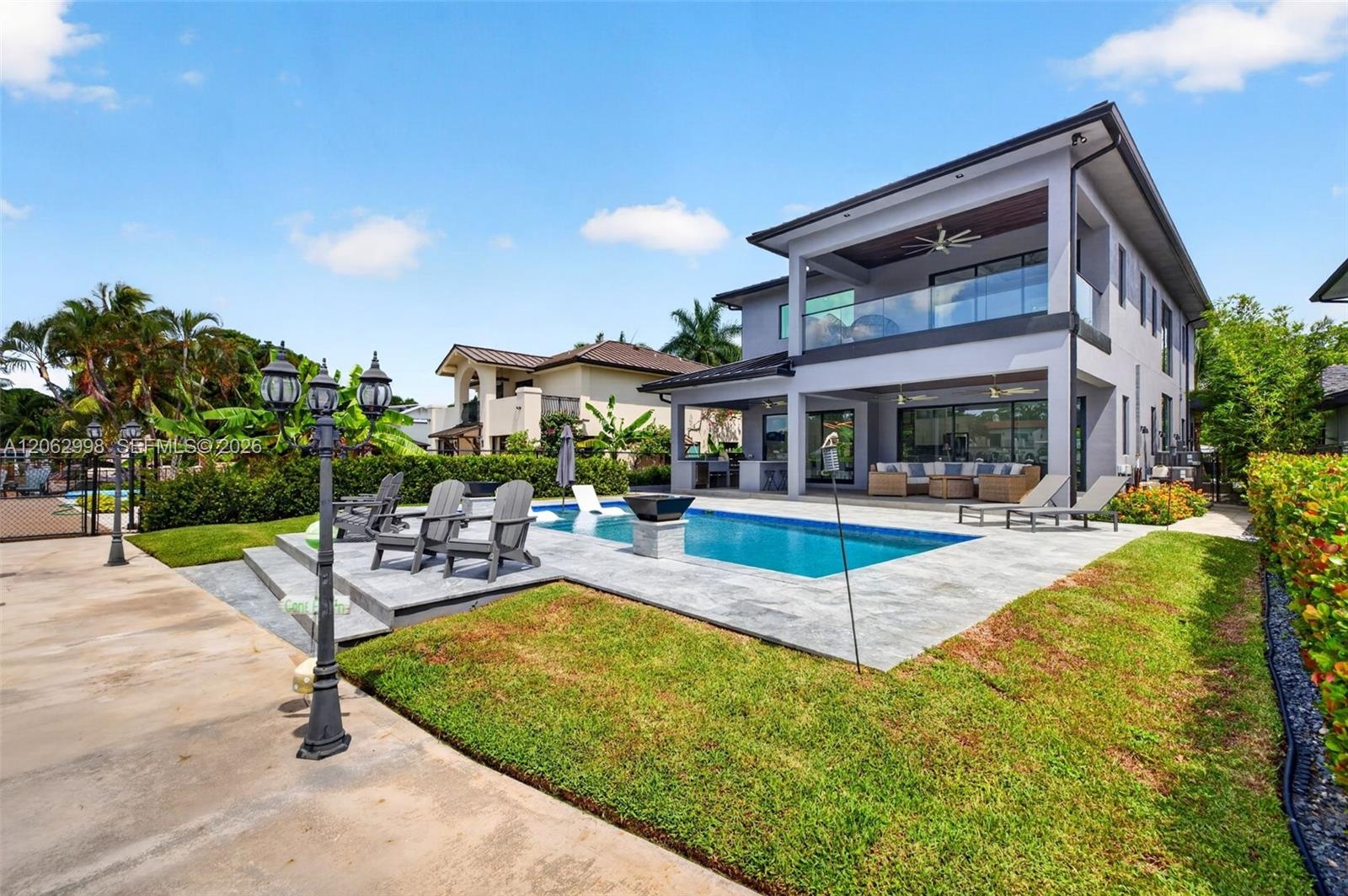View from the new concrete dock and seawall to the Salt chlorinated pool w/ water features, LED color changing light, sun shelf with umbrella hole and
