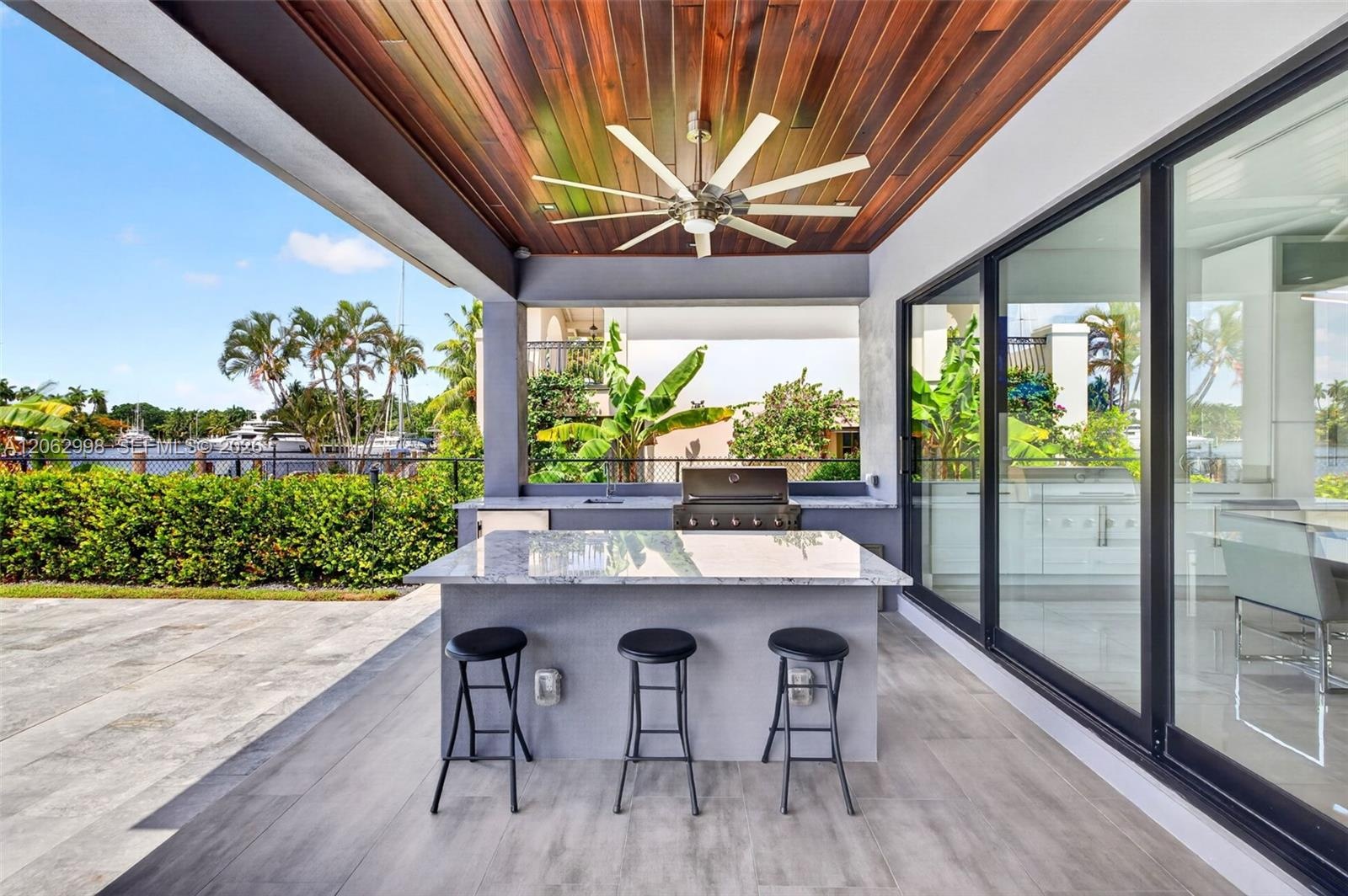 Covered patio w/ T&G ceilings, fans, fire pit seating and outdoor kitchen overlooks the gorgeous wide New River views and pool area