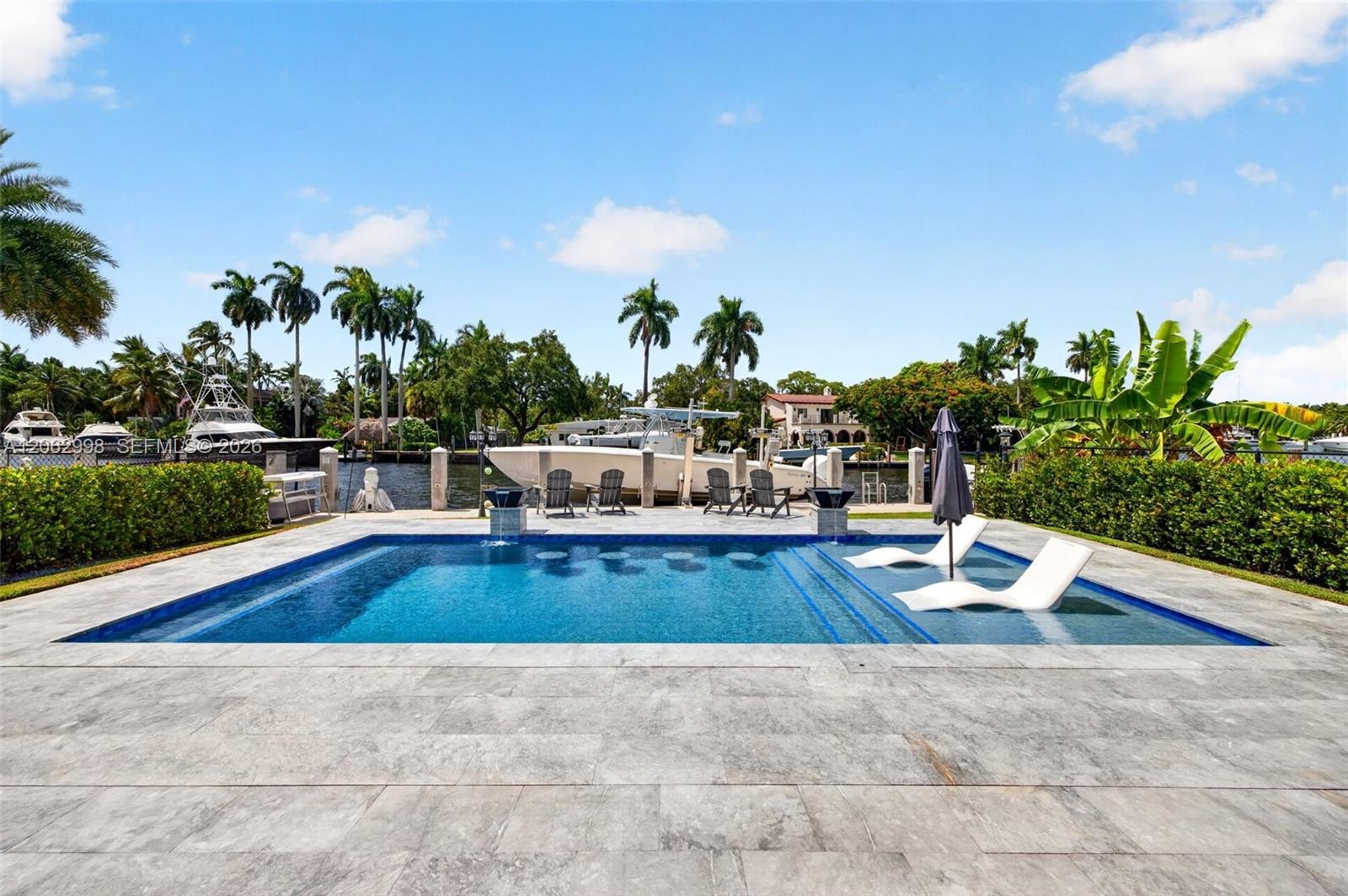 Salt chlorinated pool w/ water features, LED color changing light, sun shelf with umbrella hole and in water stools. Stone decking surrounds the pool