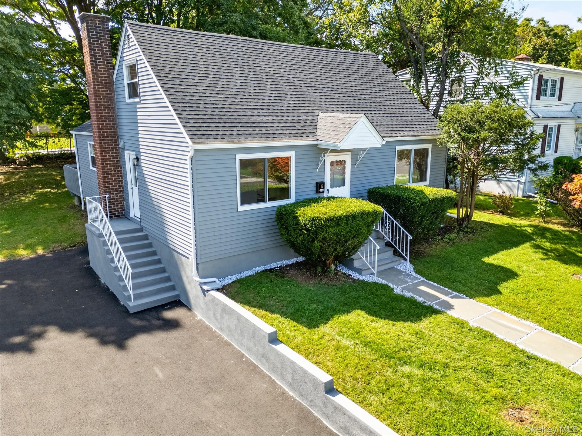 Gray siding exterior with white trim, a gabled roof, and a prominent brick chimney