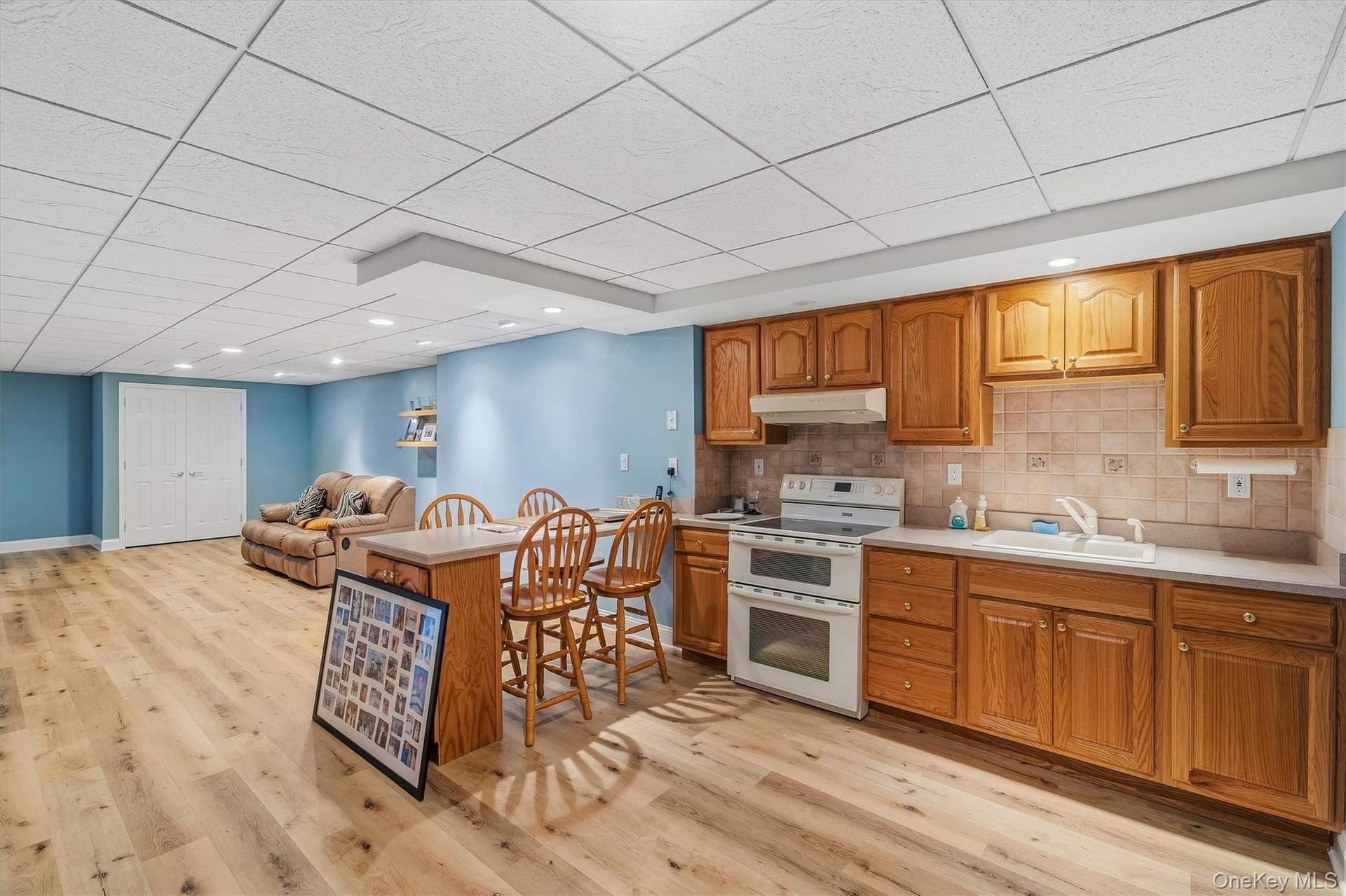 Full kitchen with wood cabinetry, light countertops, and tile backsplash