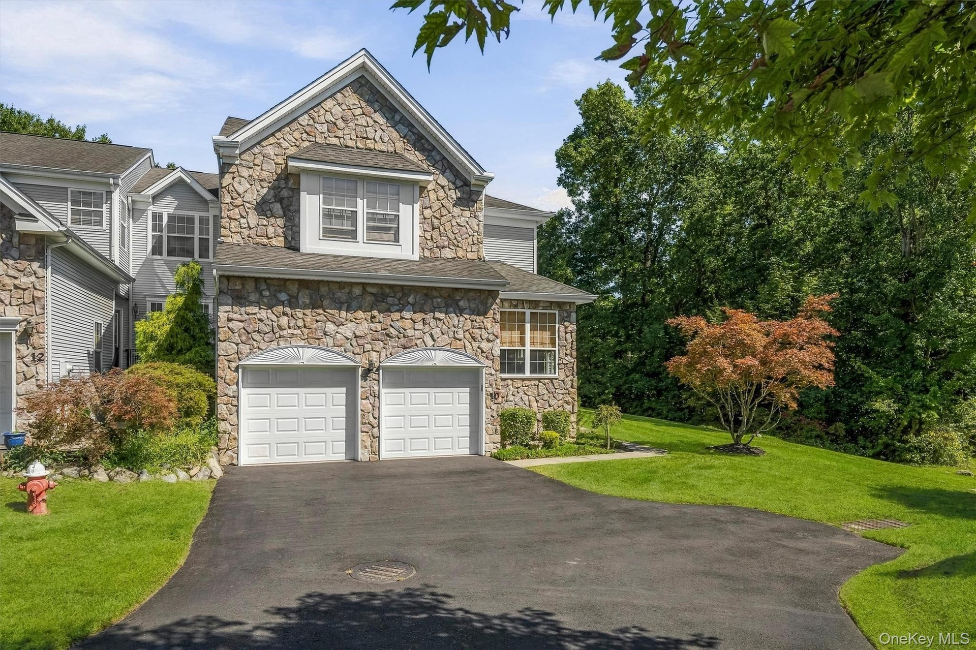Stone exterior with a two-car garage, pitched roofline and dormer window