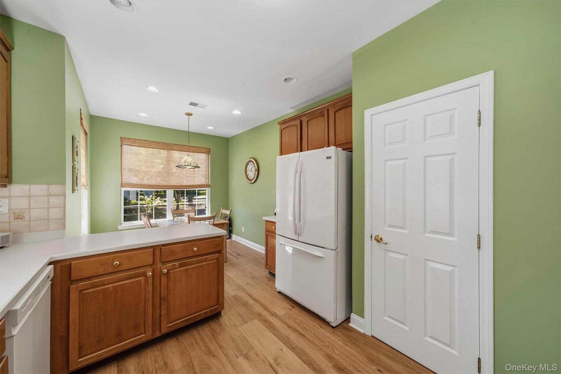 Kitchen featuring wood-finish flooring, wood cabinetry with gold-tone hardware, a tiled backsplash, and recessed lighting