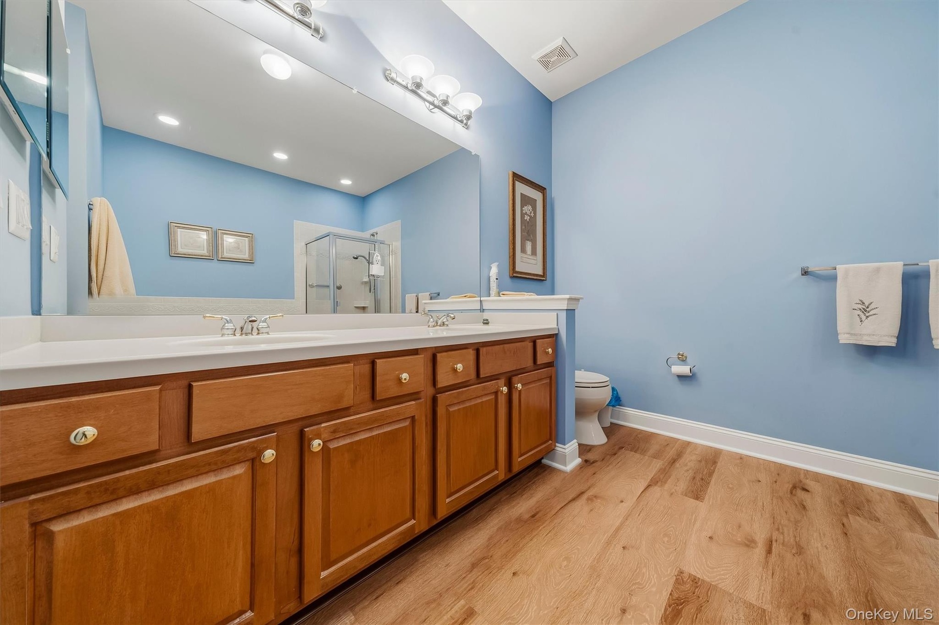 Double vanity with wood-finish cabinetry, white countertop, and dual sinks