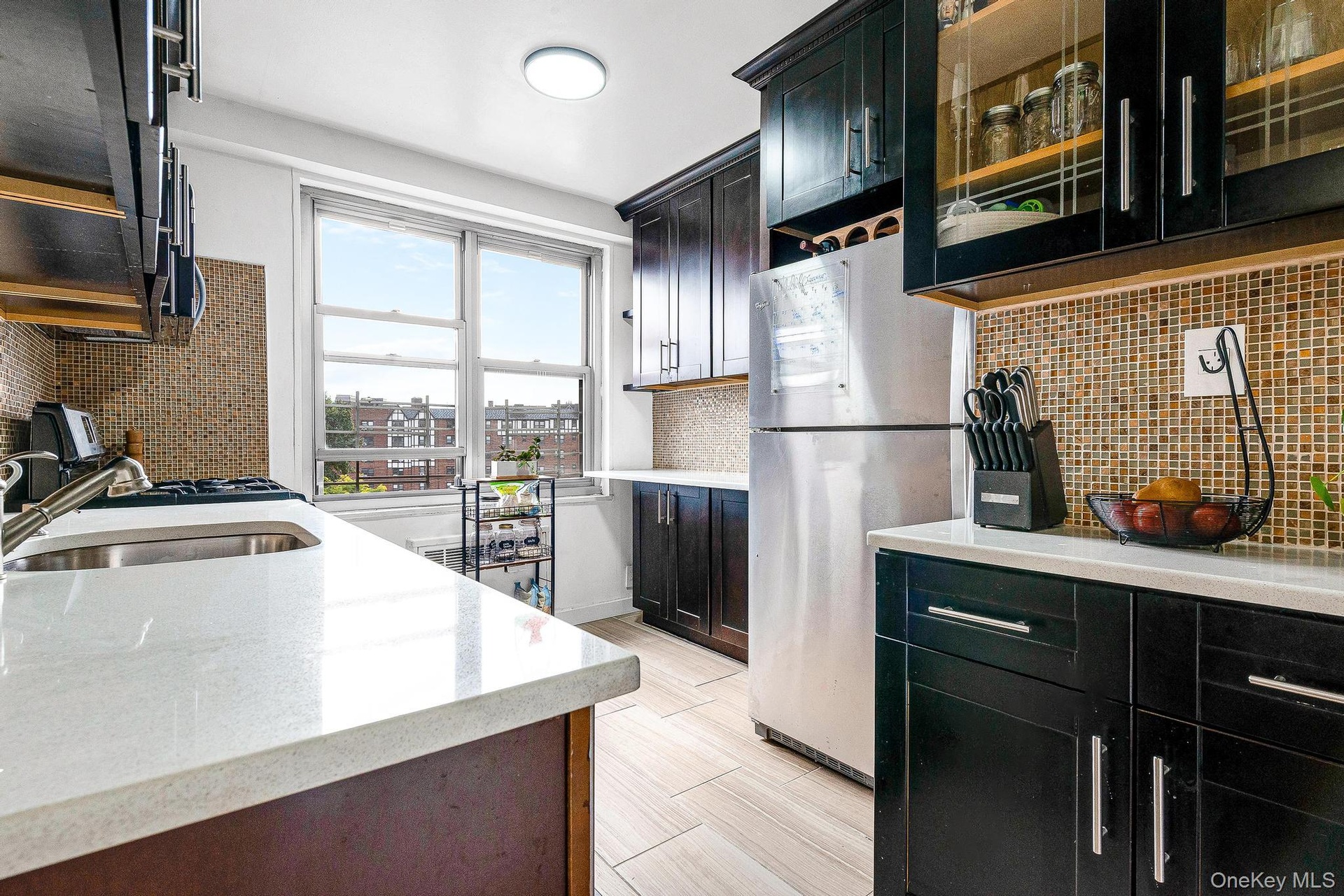 Kitchen featuring dark cabinets, backsplash, and freestanding refrigerator