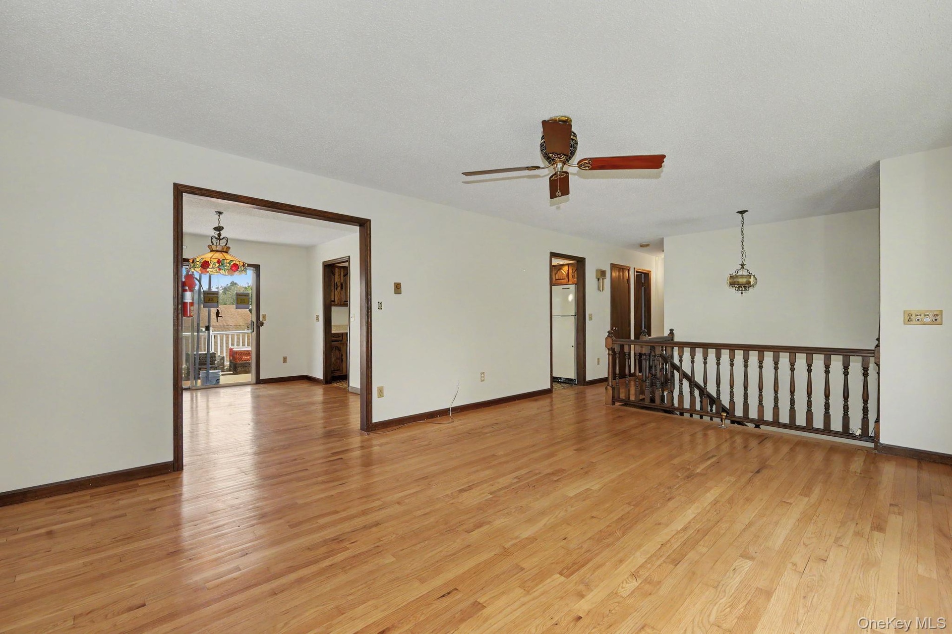 Living room with hardwood floors leading to dining room and hallway