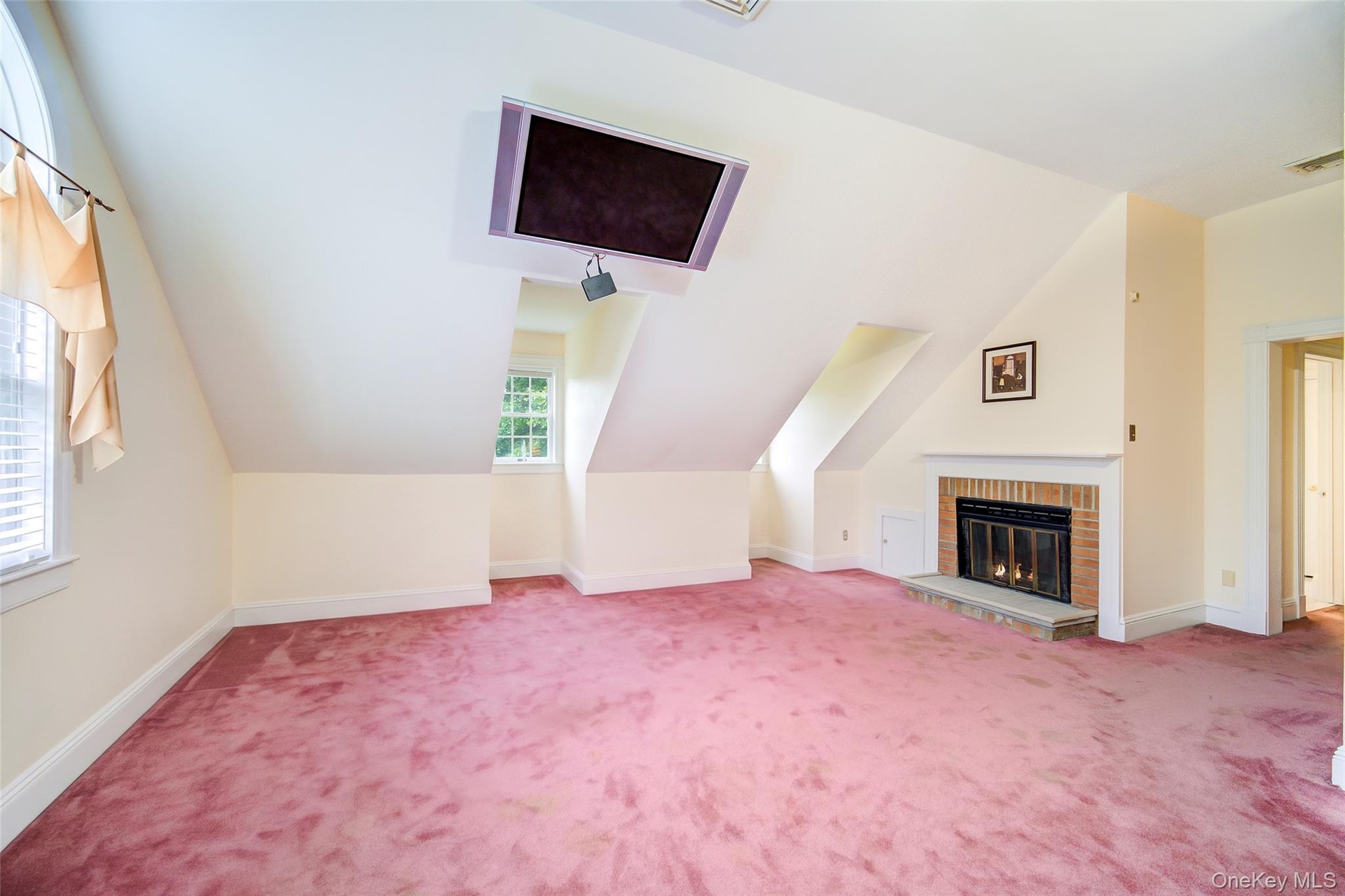 Sloped ceiling room featuring a brick fireplace with stone hearth, multiple windows for sun/moonlight